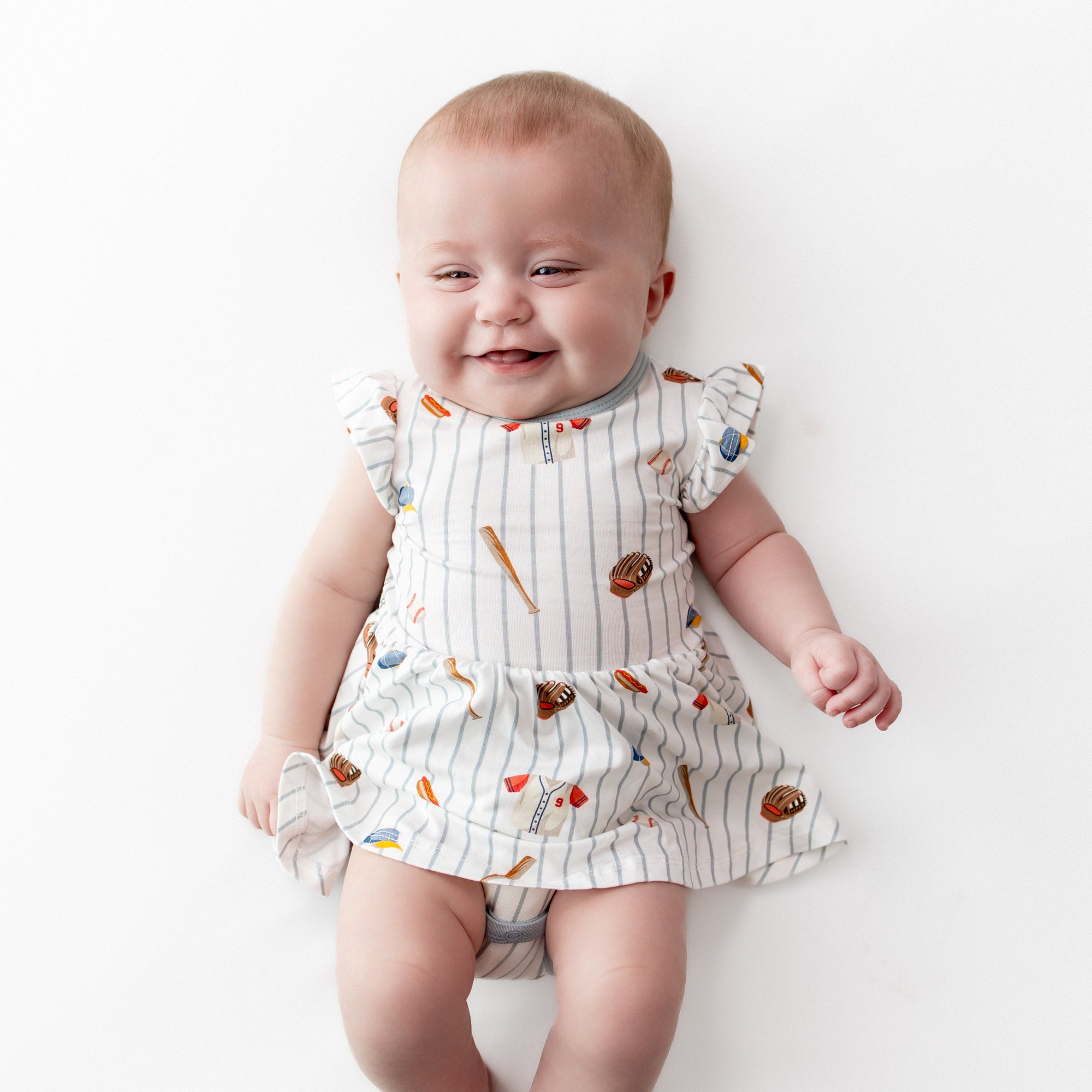 Smiling infant wearing the Twirl Bodysuit Dress in Home Run