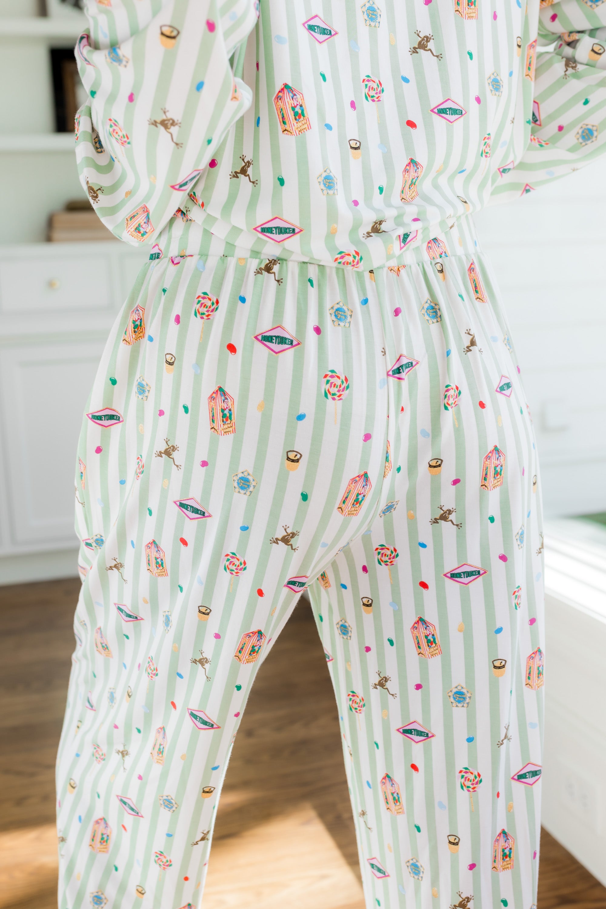 Back side of Long-Sleeved Women's Pajama Set pajamas with colorful Harry Potter patterns on a green and white striped fabric.
