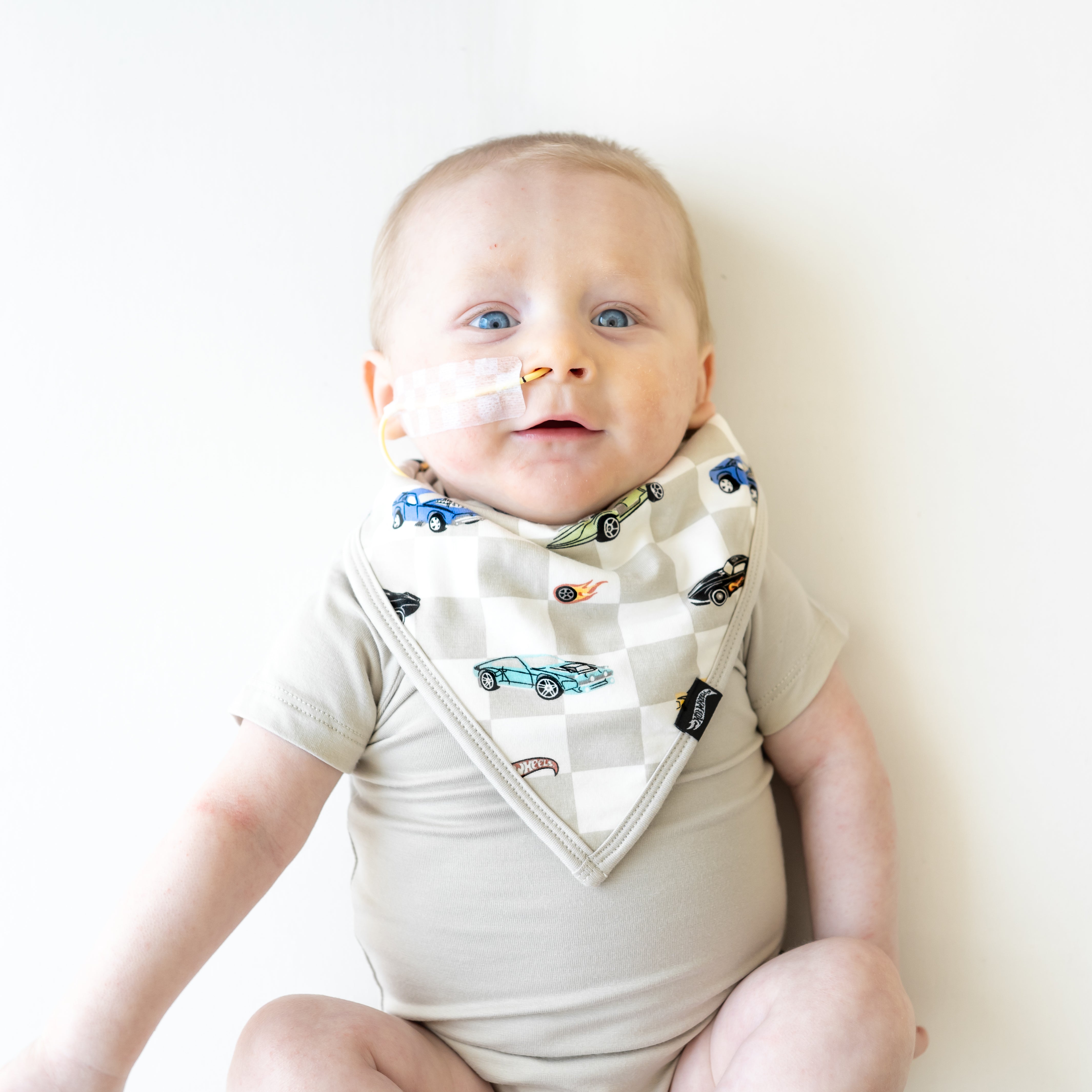 Infant wearing the Bib in Fast and Fierce paired with an Oat Short Sleeve Bodysuit