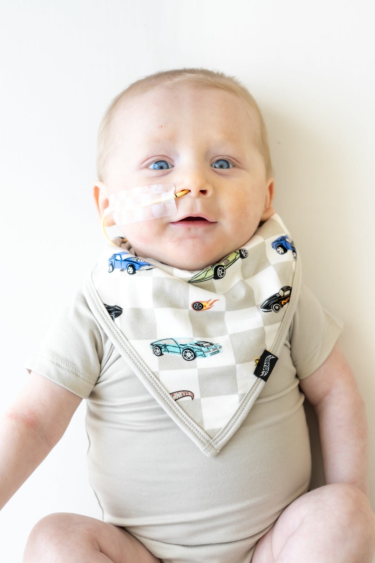 Infant wearing the Bib in Fast and Fierce paired with an Oat Short Sleeve Bodysuit