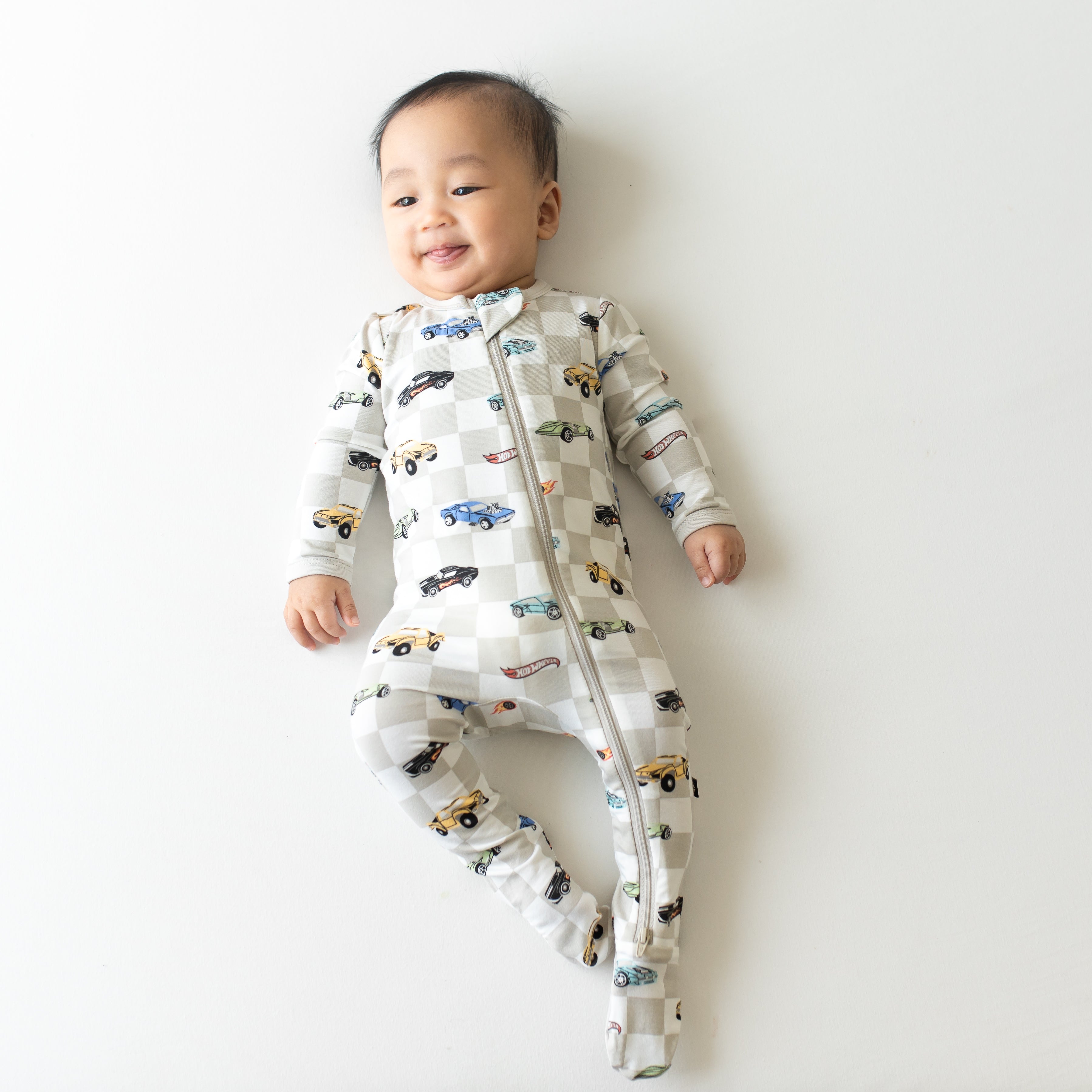 Infant smiling and sticking tongue out wearing the Zippered Footie in Fast and Fierce