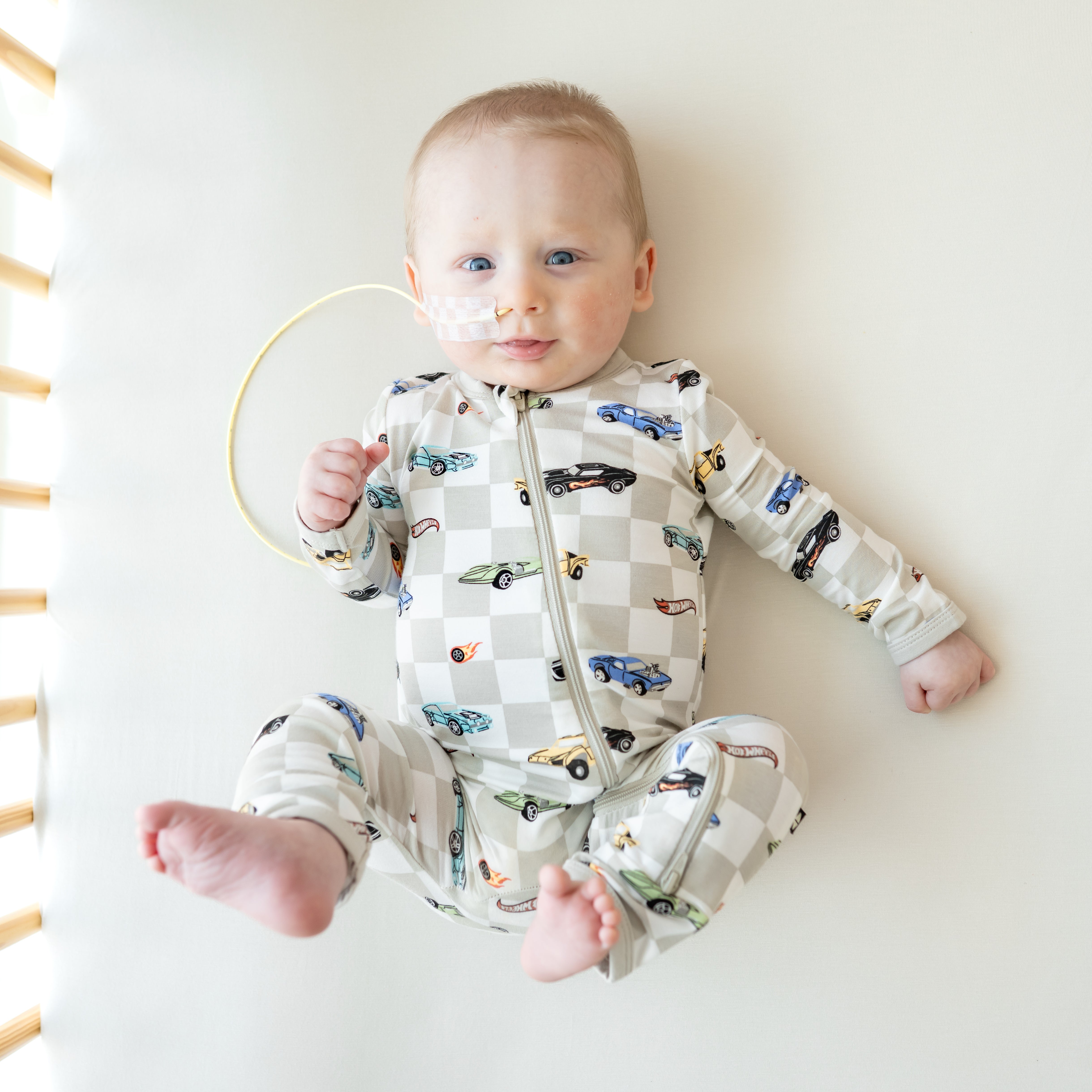 Smiling model laying in a crib wearing the Zippered Romper in Fast and Fierce