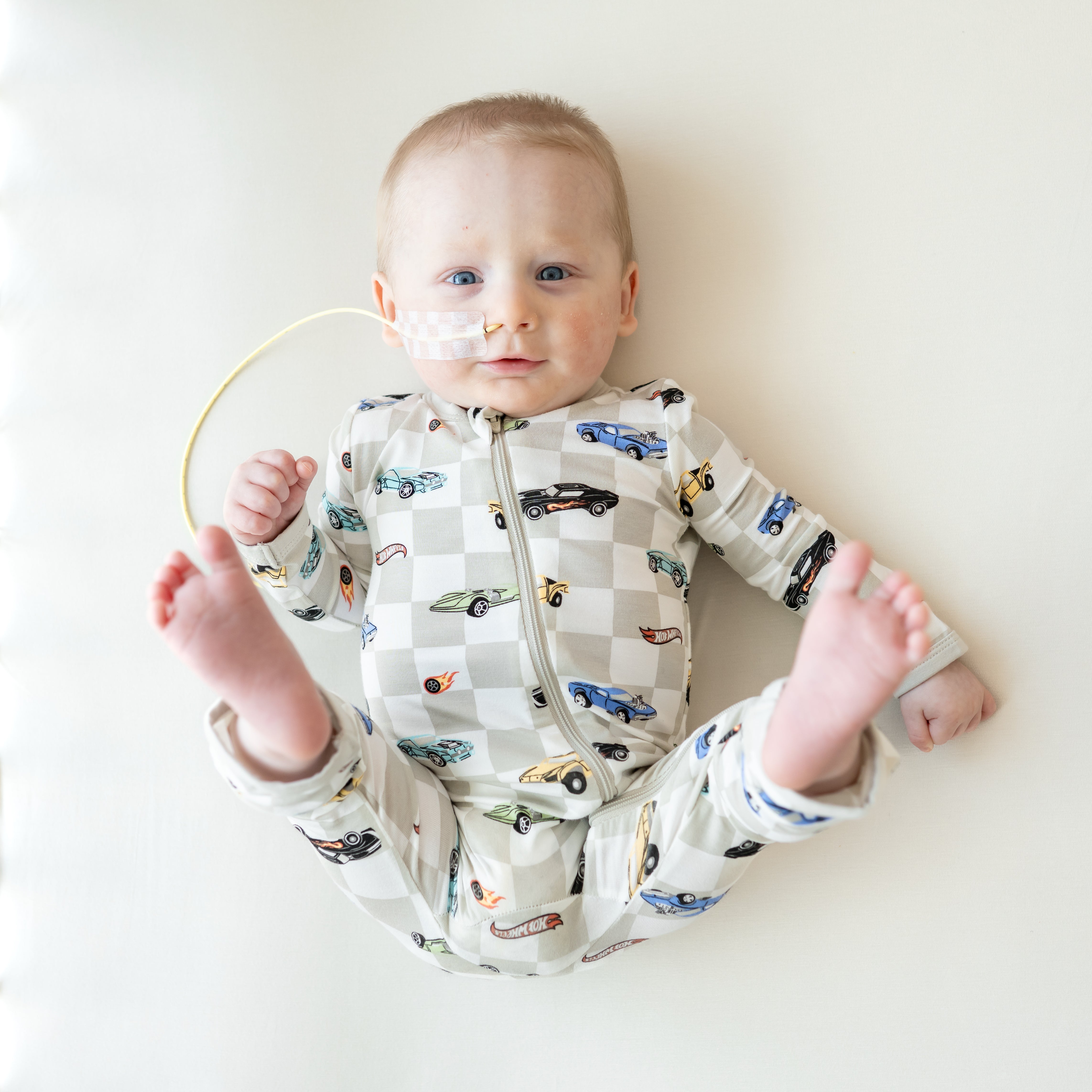 Infant laying in a crib looking at the camera with hi feet in the air wearing the Zippered Romper in Fast and Fierce