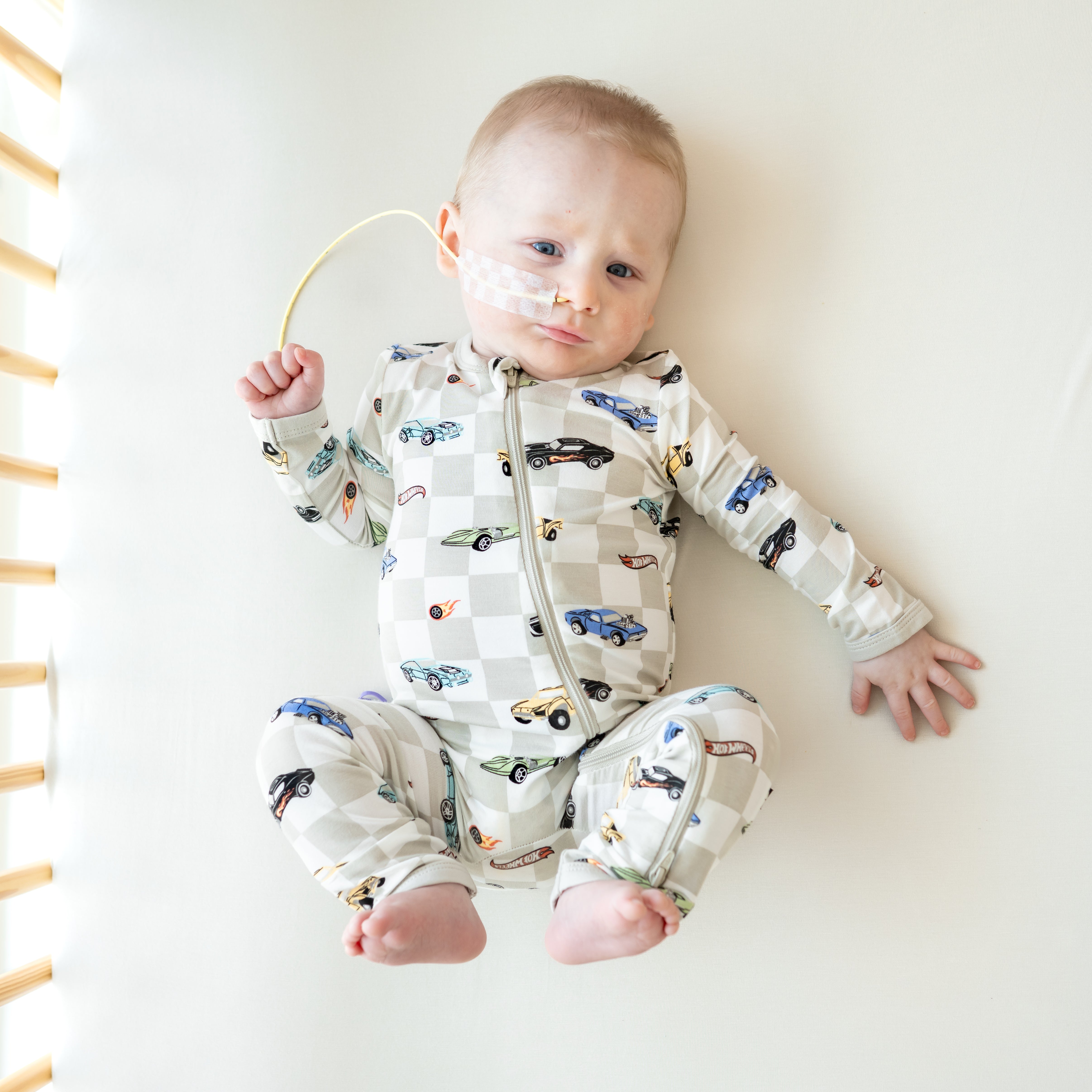 Infant laying in a crib with his feet in the air wearing the Zippered Romper in Fast and Fierce