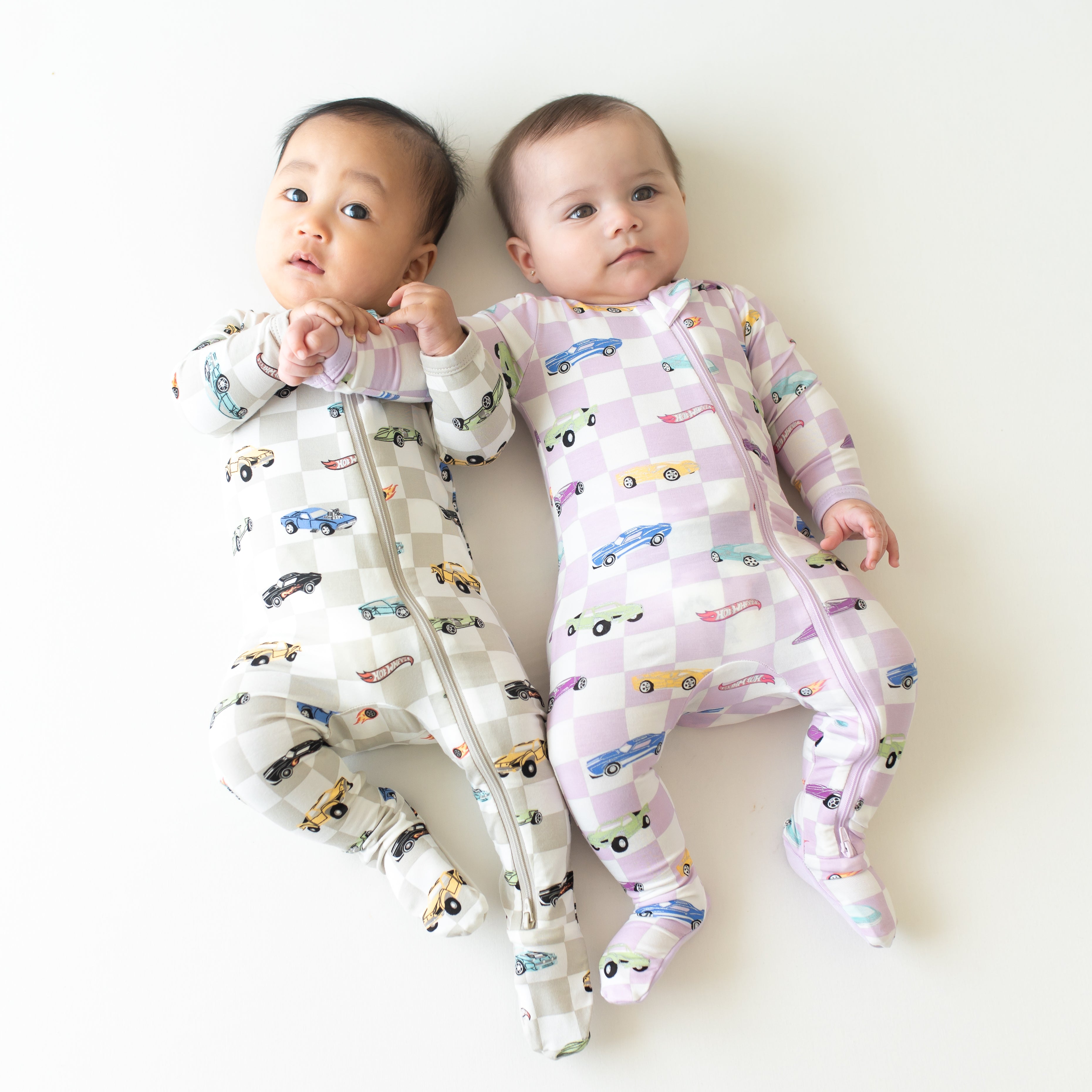 Two infants laying side by side wearing the zippered footies from the Hot Wheels™ collection