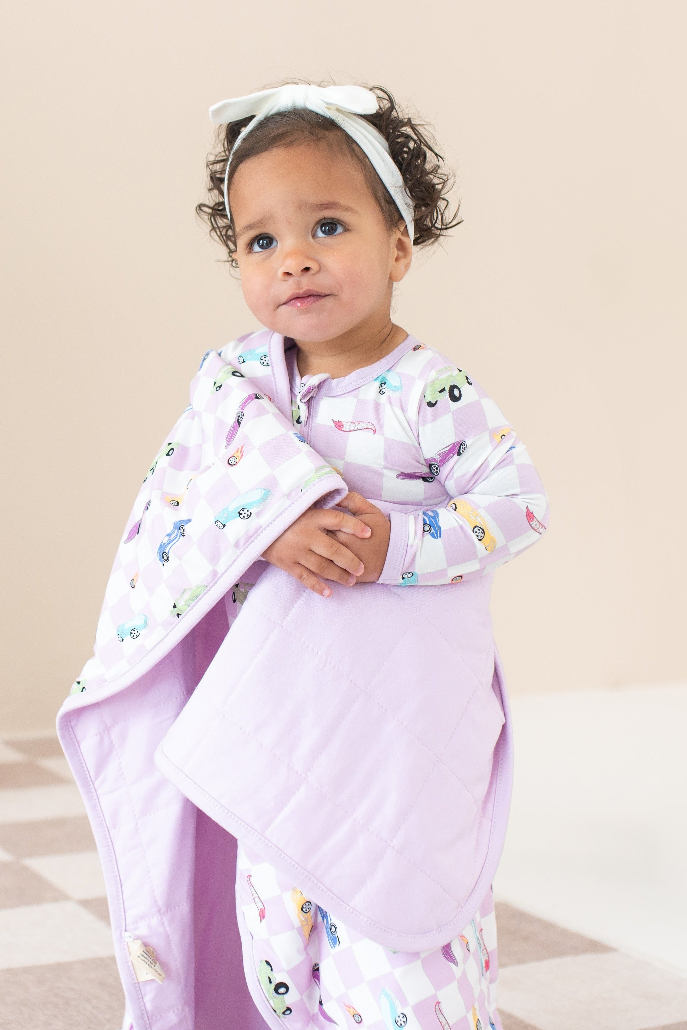 Girl wearing purple Hot Wheels pajamas wrapped in matching Baby Blanket in Sparkles and Speed TOG 1.0