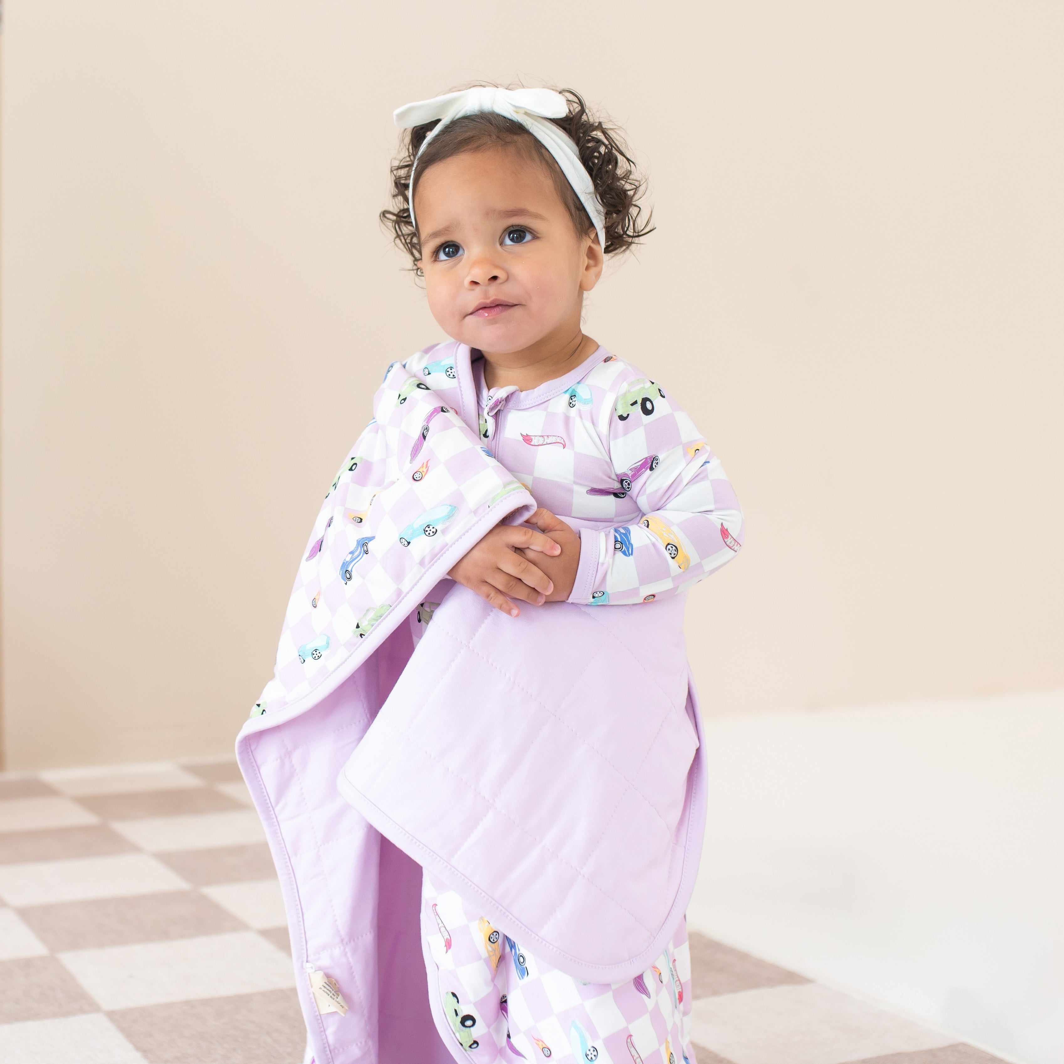 Girl wearing purple Hot Wheels pajamas wrapped in matching Baby Blanket in Sparkles and Speed TOG 1.0