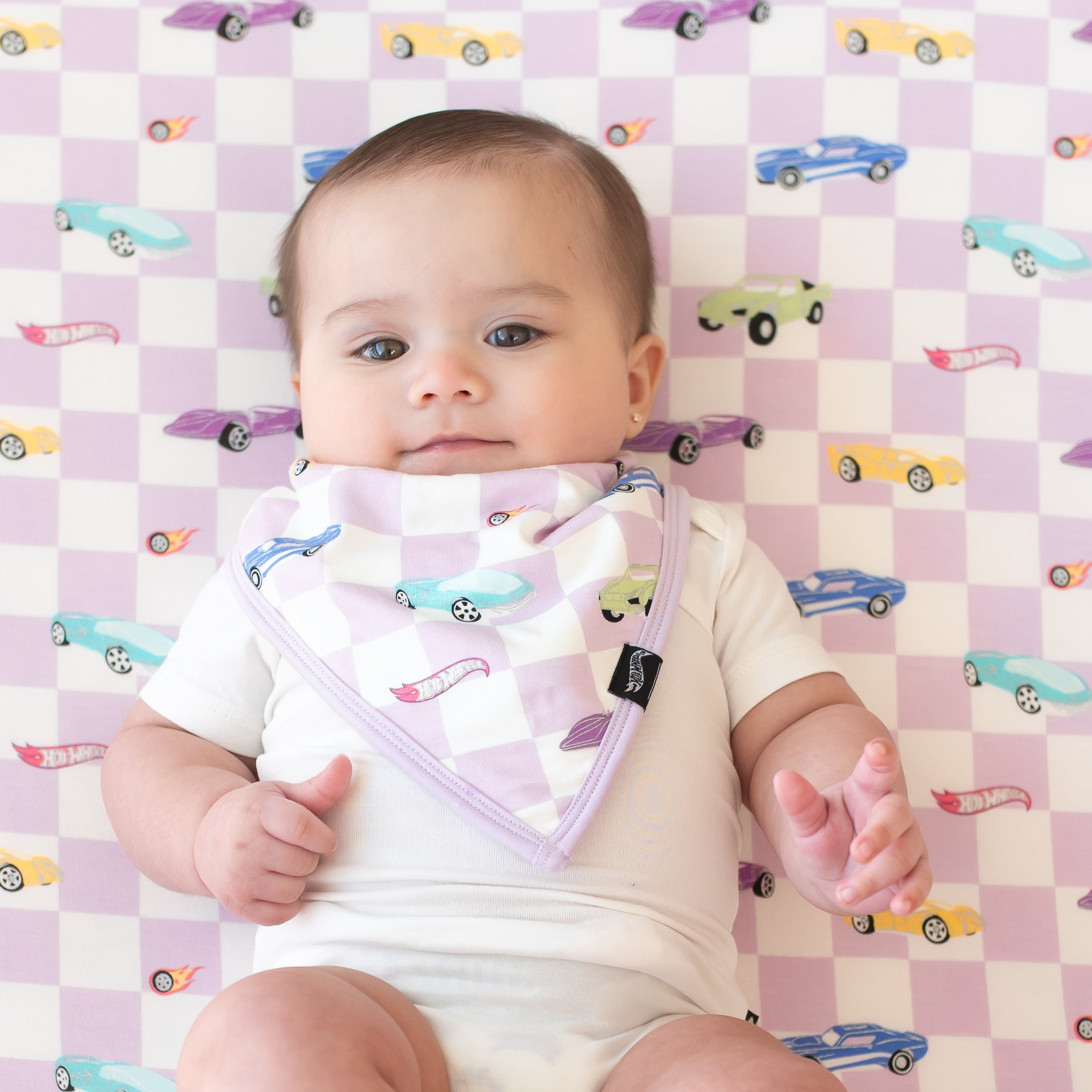 Infant wearing a Bib in Sparkles and Speed laying a matching blanket wearing a Cloud Short Sleeve Bodysuit