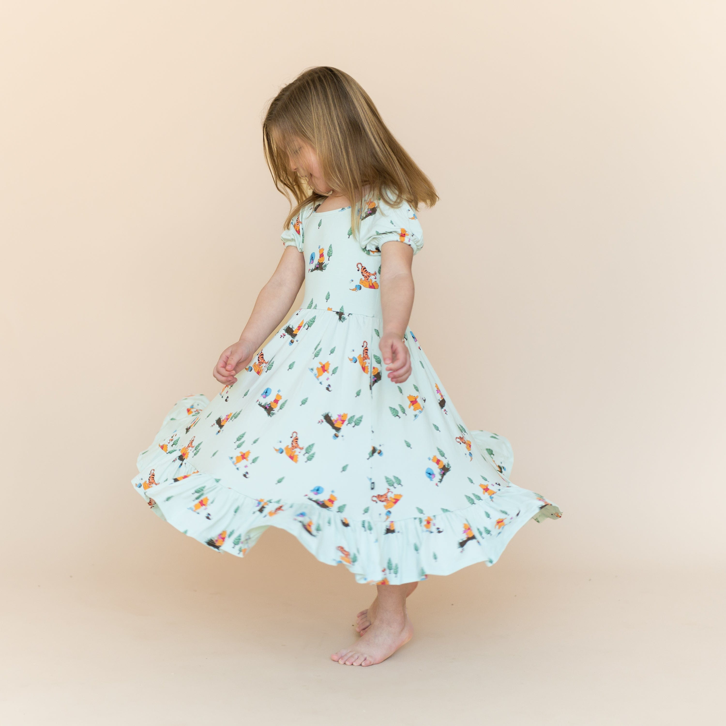 Young girl twirling wearing the Puff Sleeve Twirl Dress in Winnie the Pooh Hundred Acre Wood
