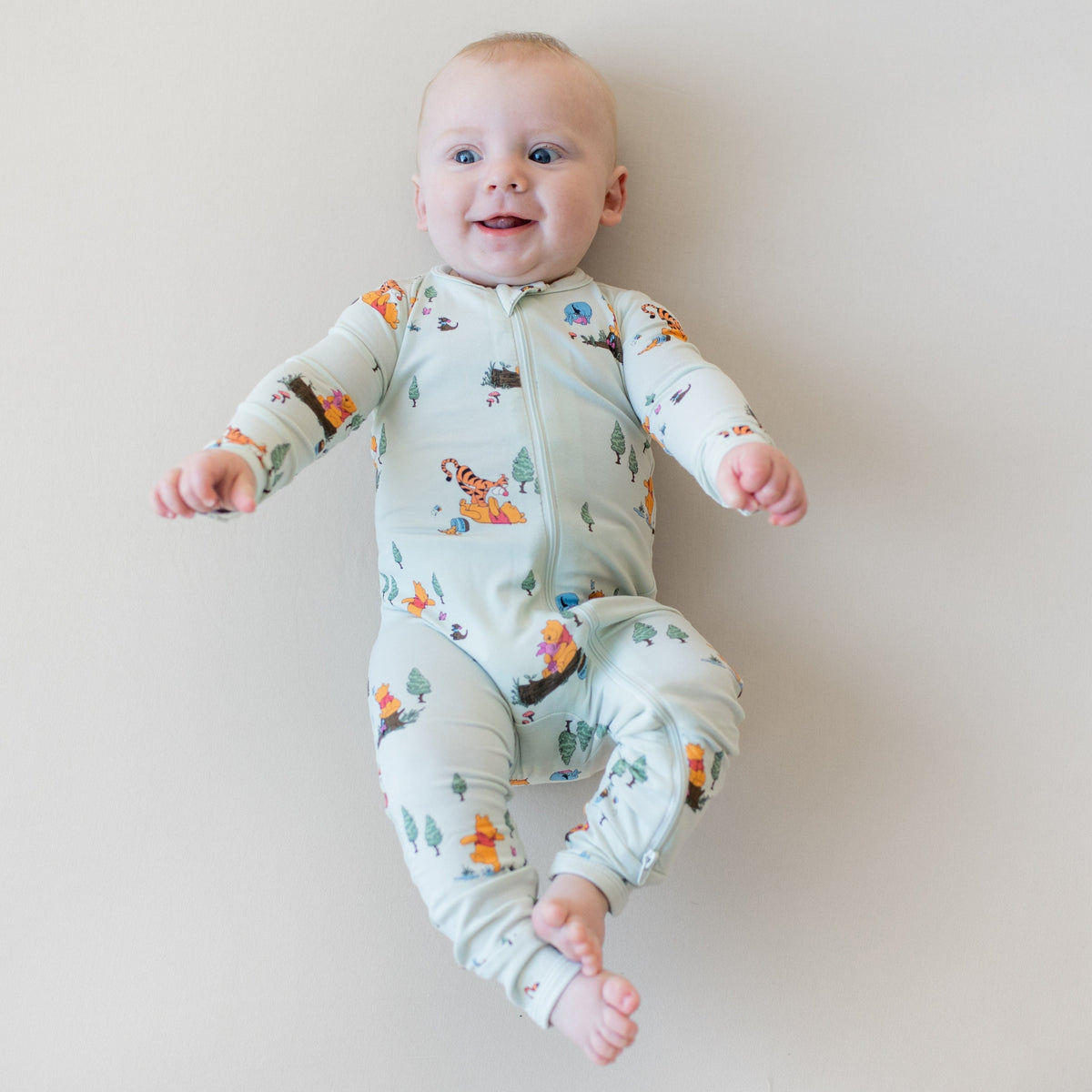 Smiling model wearing the Zippered Romper in Winnie the Pooh Hundred Acre Wood