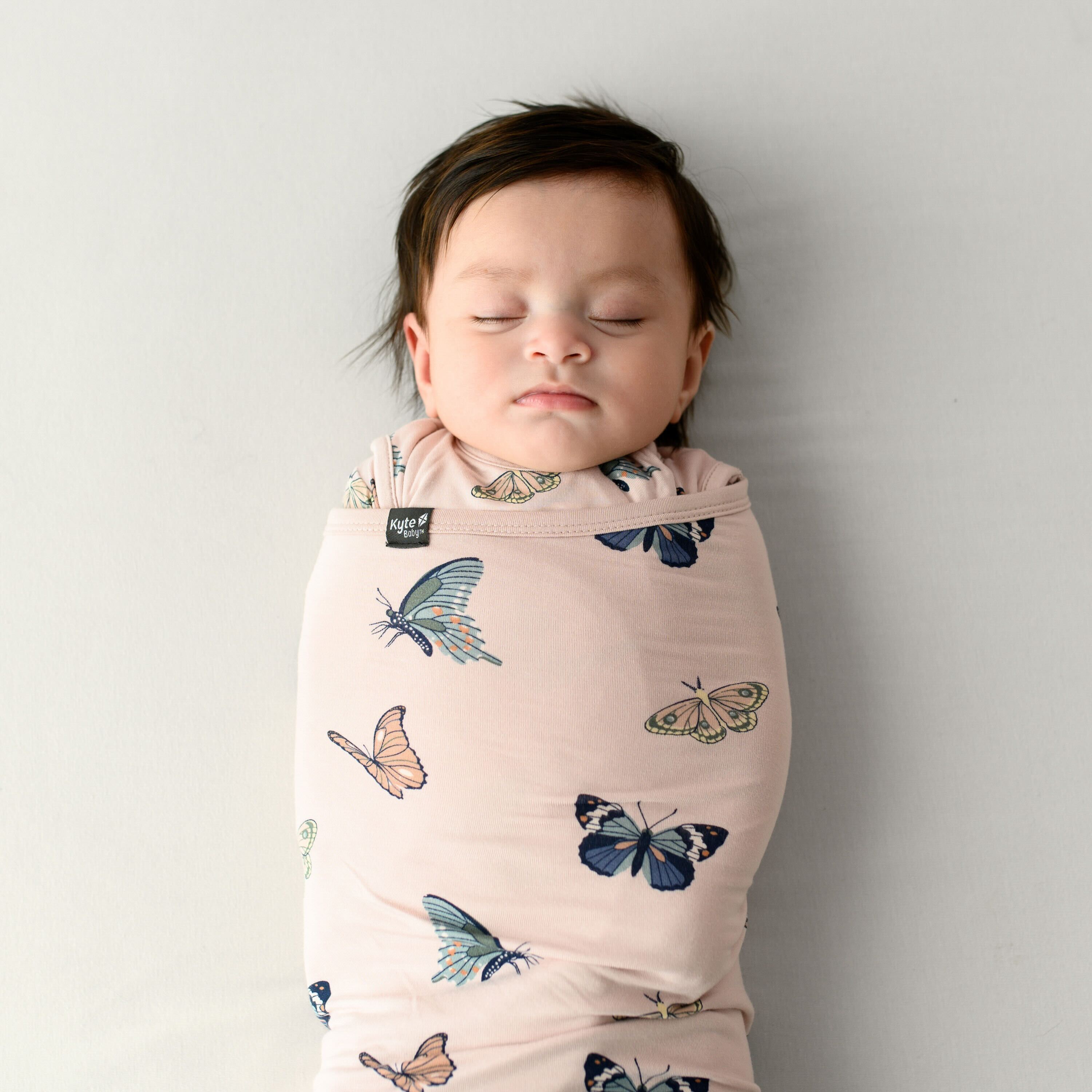 Close up of sleeping baby swaddled in the 0.5 TOG Sleep Bag Swaddler in Blush Butterfly