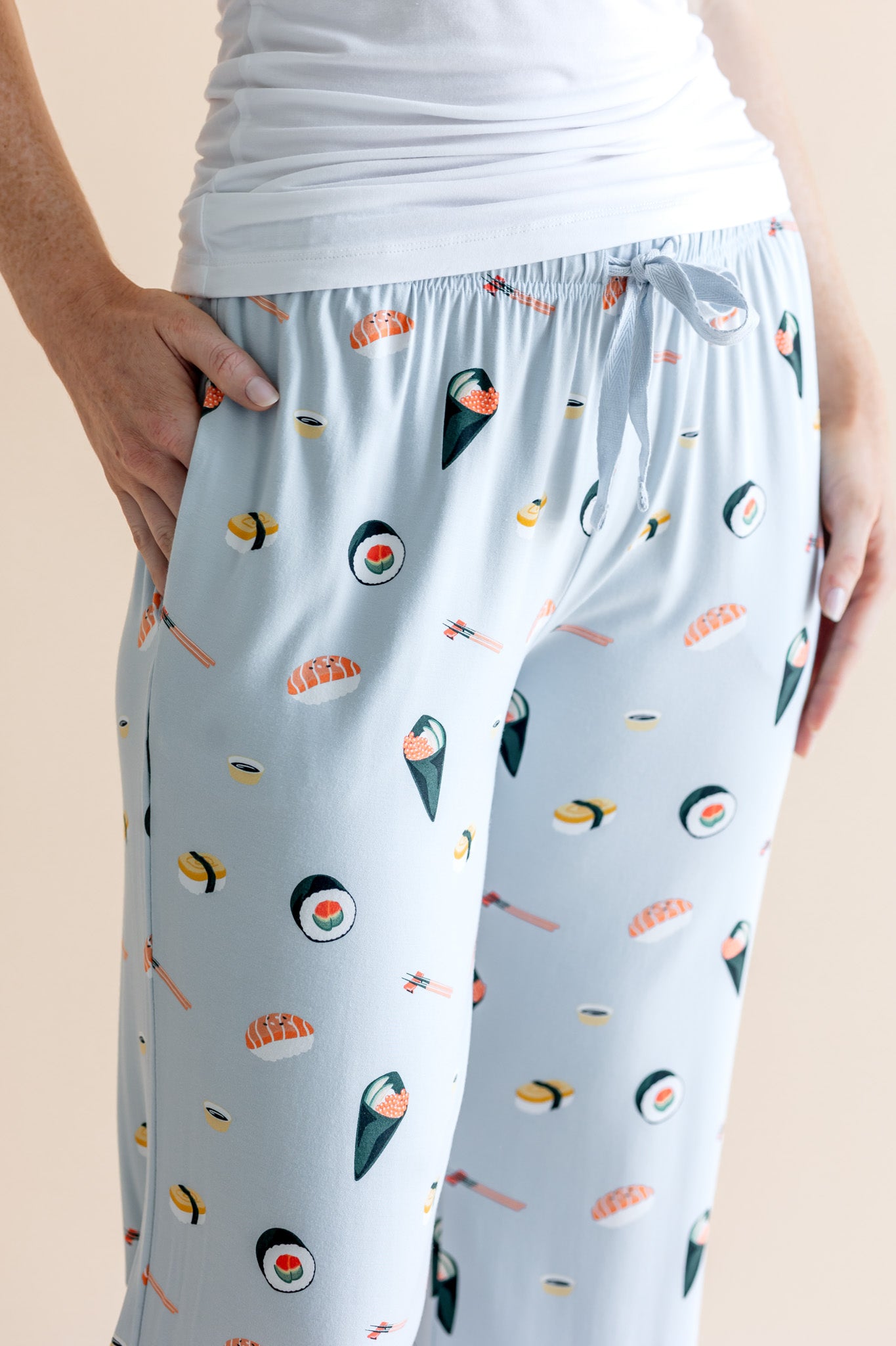 Model wearing blue Women's Lounge Pants with pockets in Sushi print under white camisole on a beige background