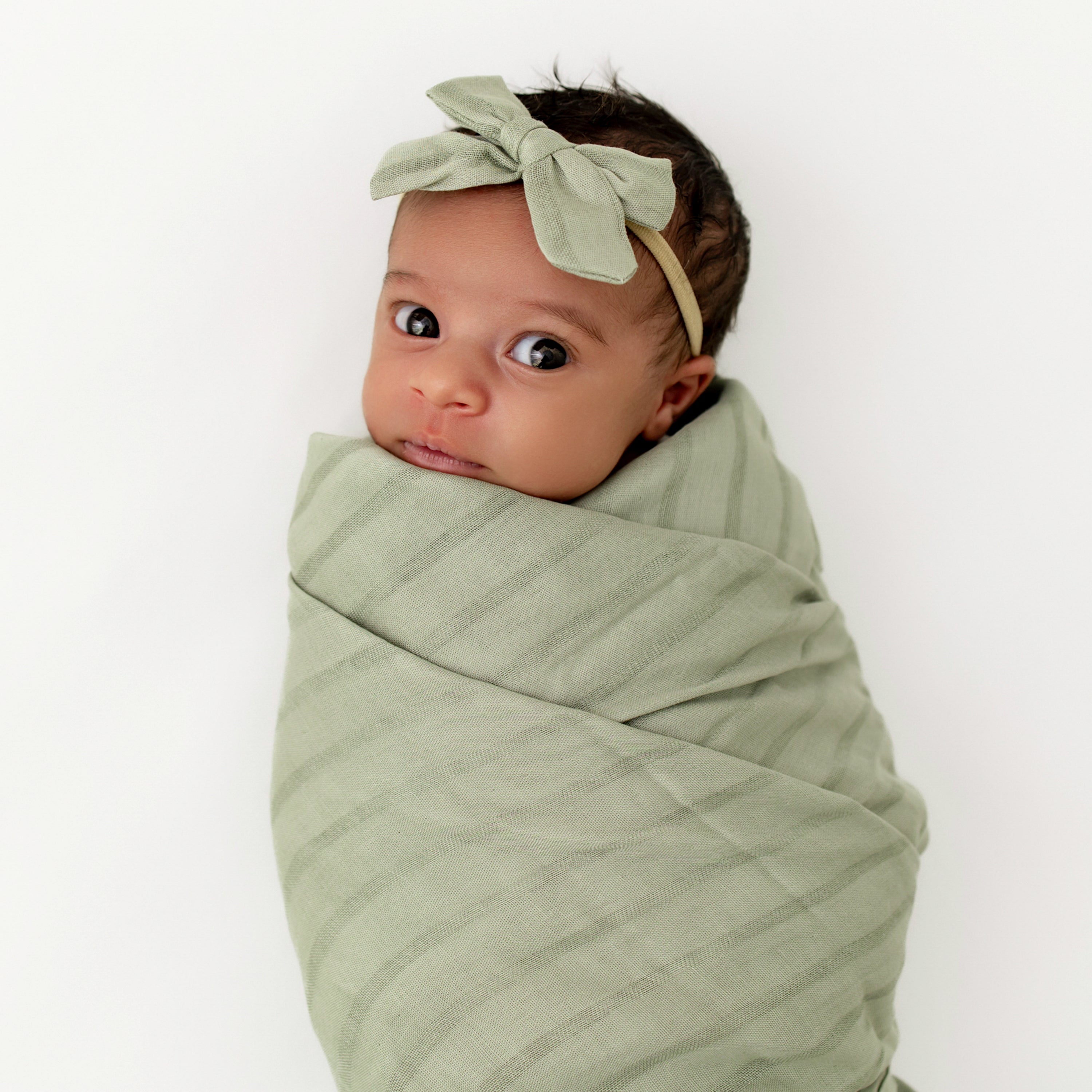Newborn wearing Medium Bamboo Muslin Bow in Jojoba with matching swaddle blanket