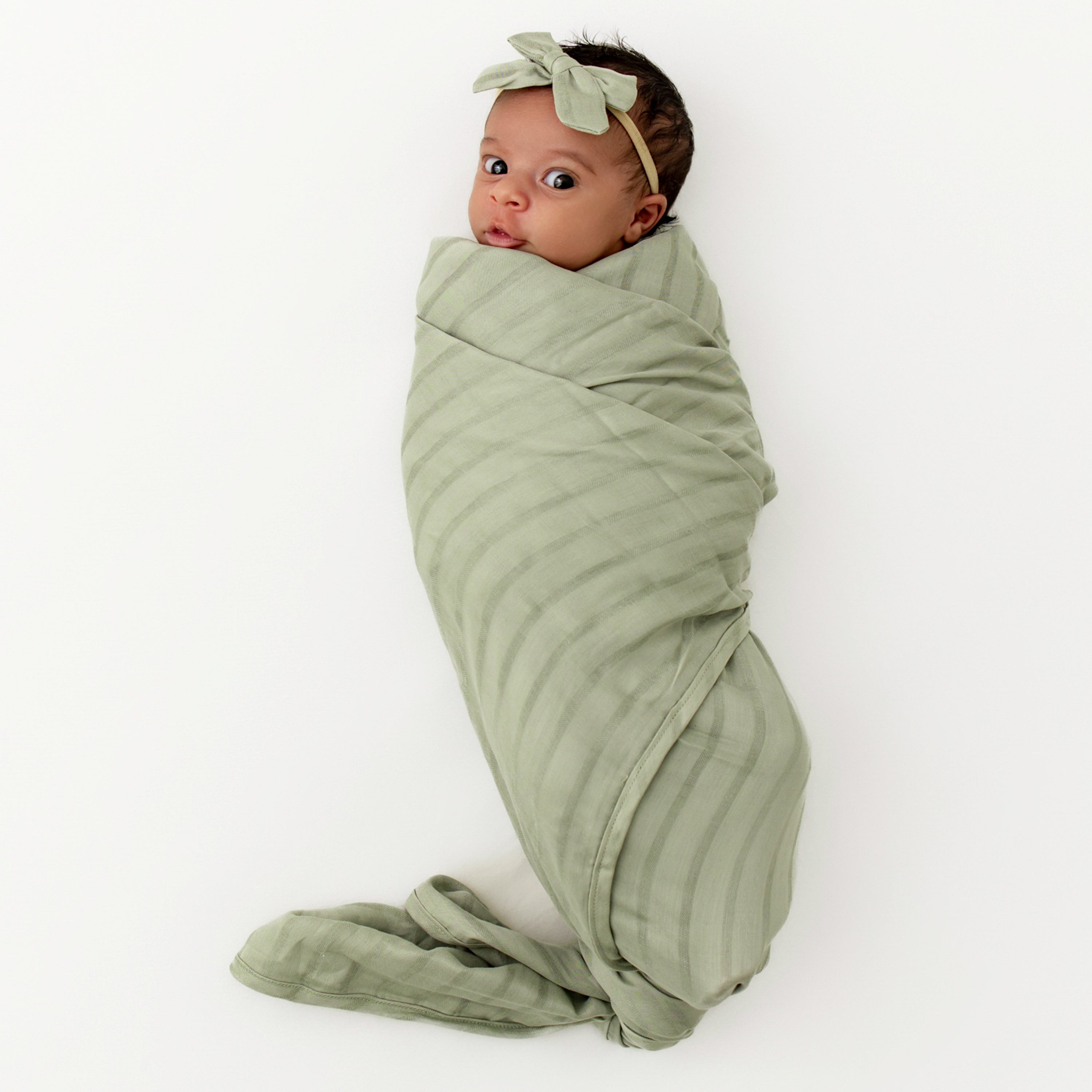 Newborn wrapped in Bamboo Muslin Swaddler Blanket in Jojoba