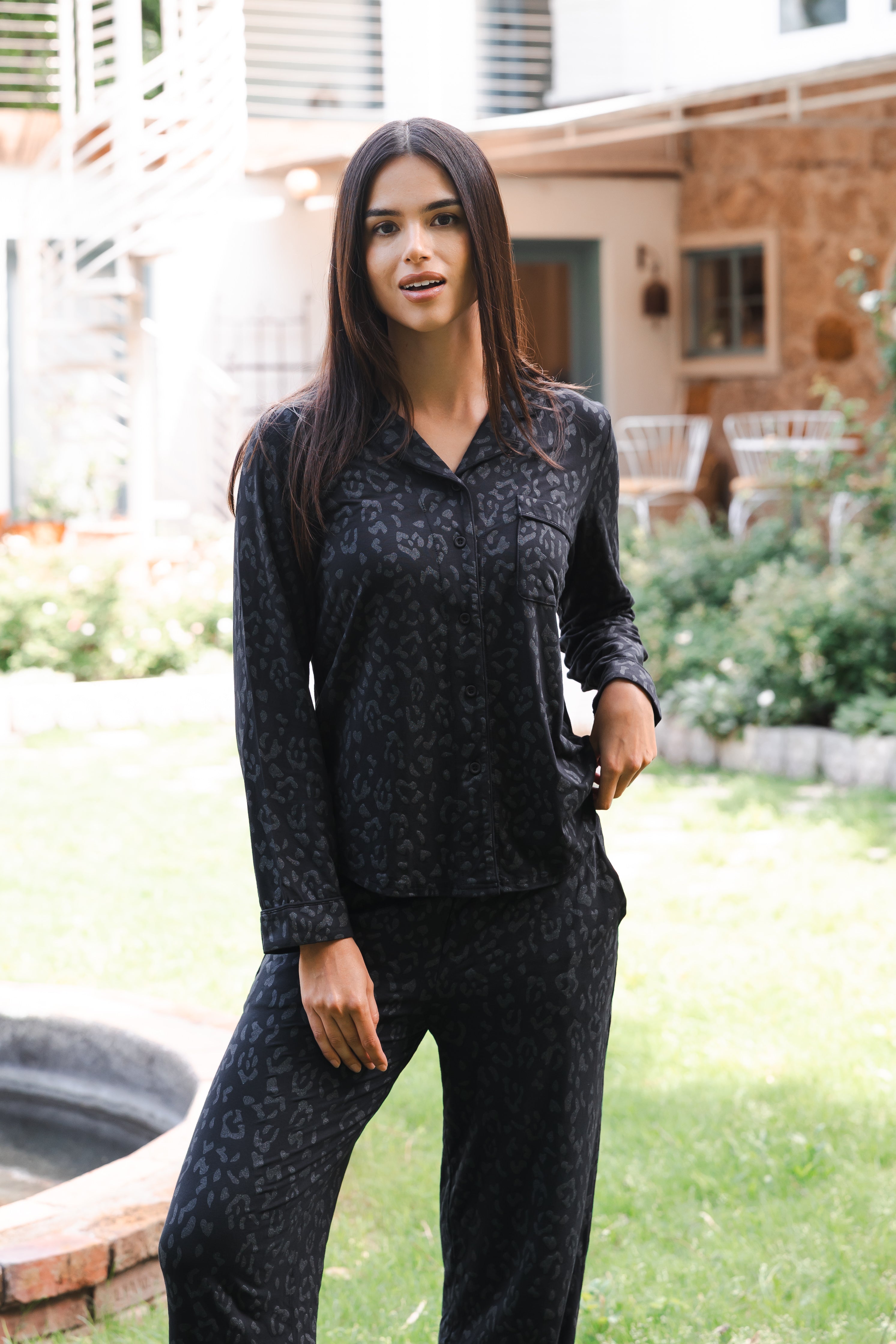 Female standing outside in front of a house wearing the Long-Sleeved Women's Pajama Set in Midnight Leopard