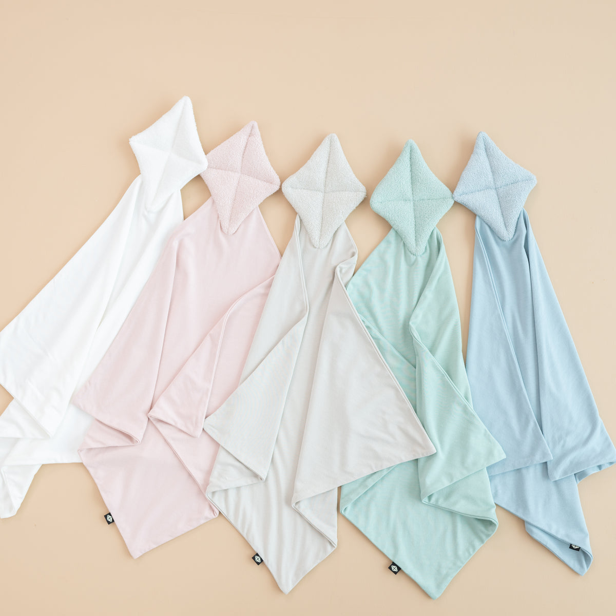 Flat lay of Kite Loveys next to cloud, blush, oat, sage and fog