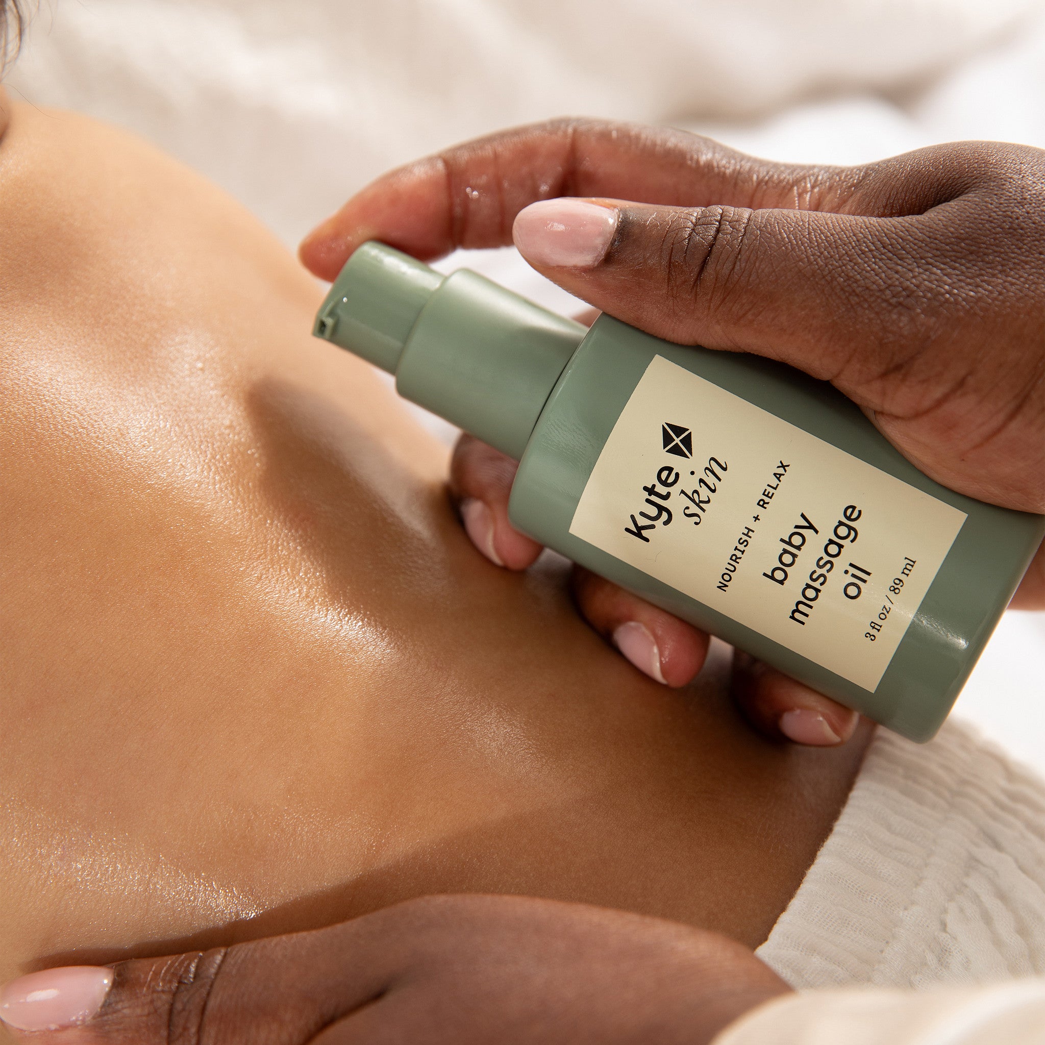 Person applying Kyte Skin baby massage oil to a child's back