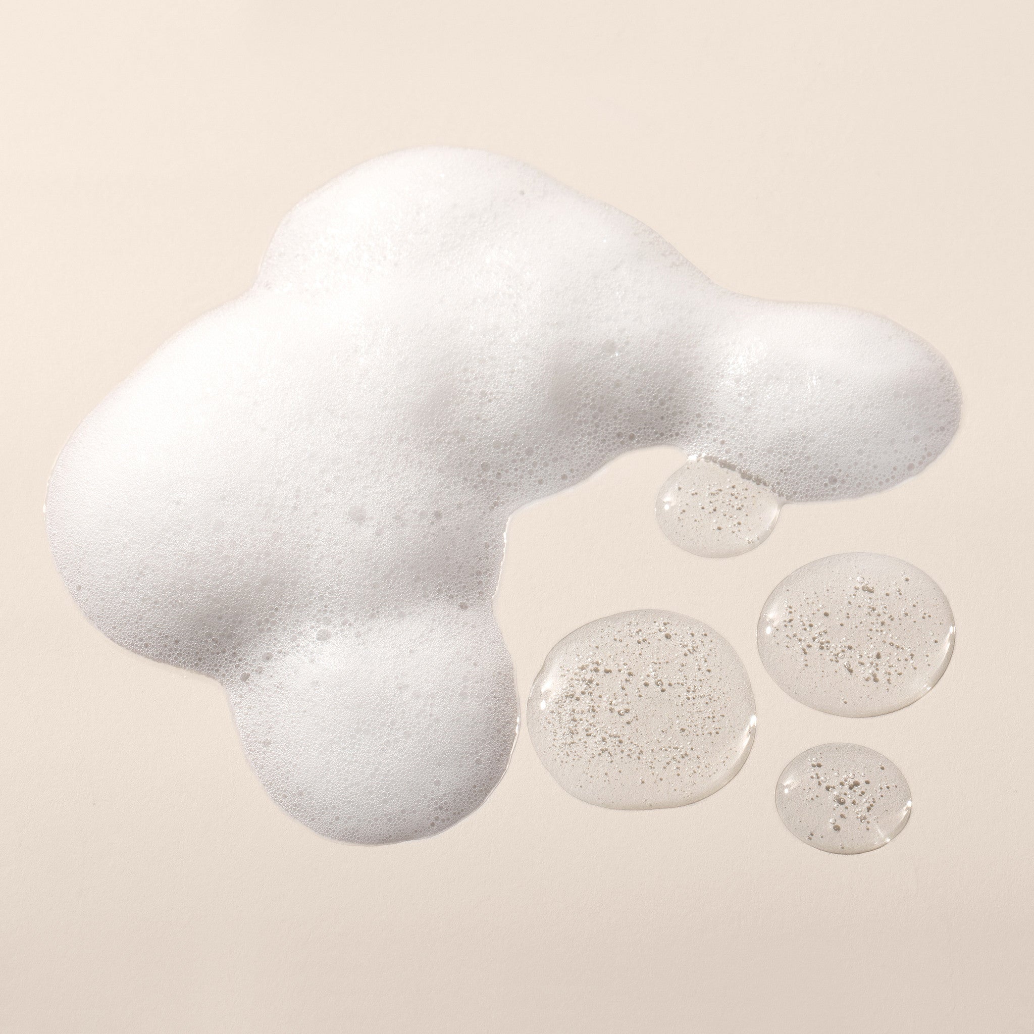 Foamy liquid texture with bubbles on a beige background