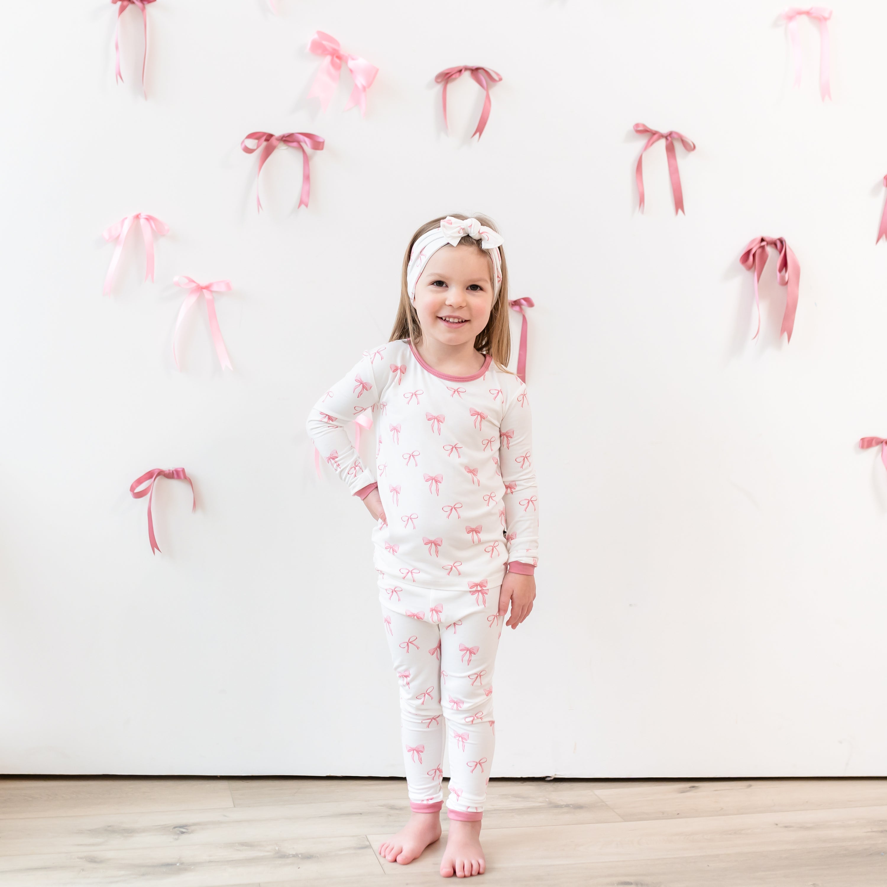 Girl modeling Long Sleeve Toddler Pajamas in Pink Bow print