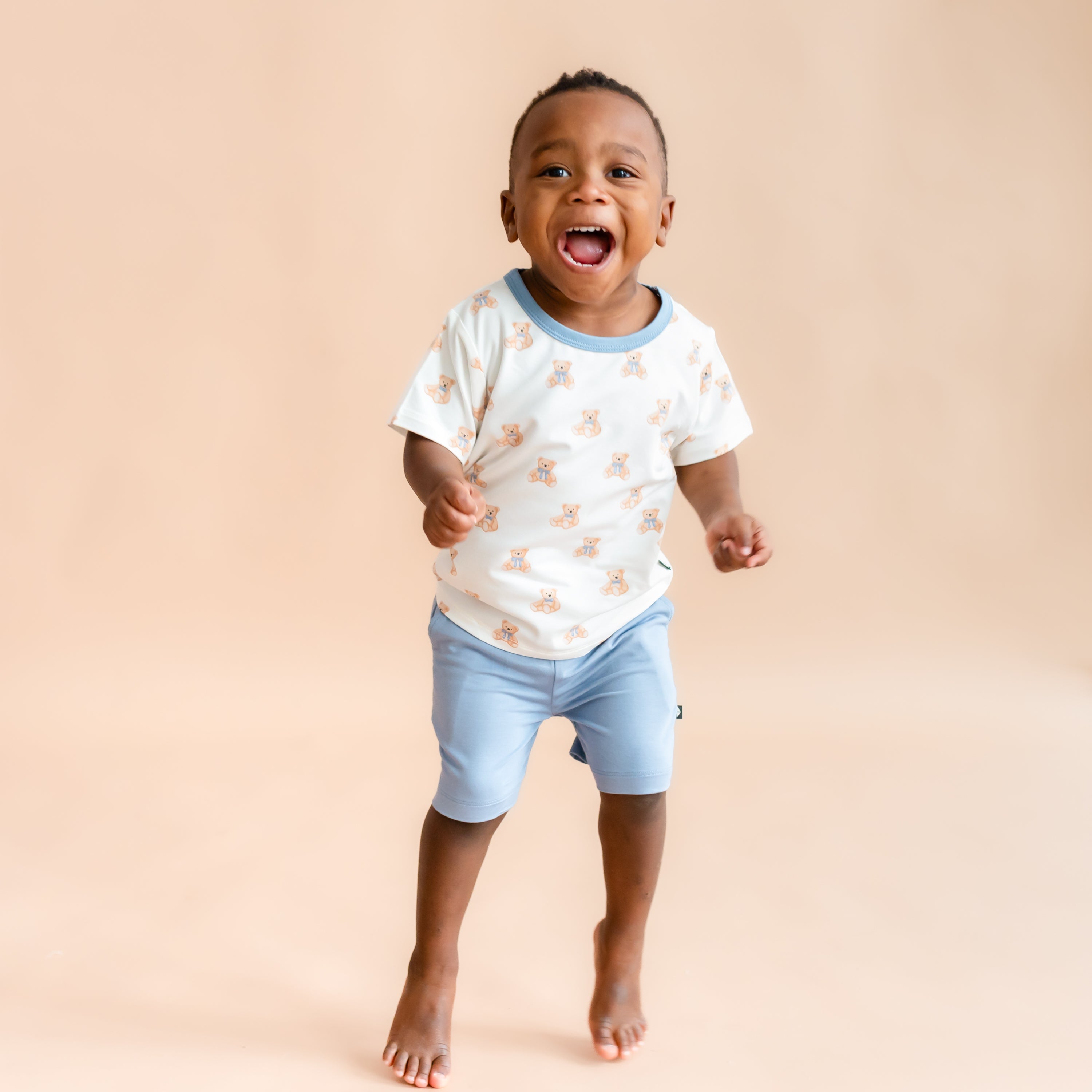 toddler boy jumping and smiling wearing Toddler Basic Tee in Teddy Bear