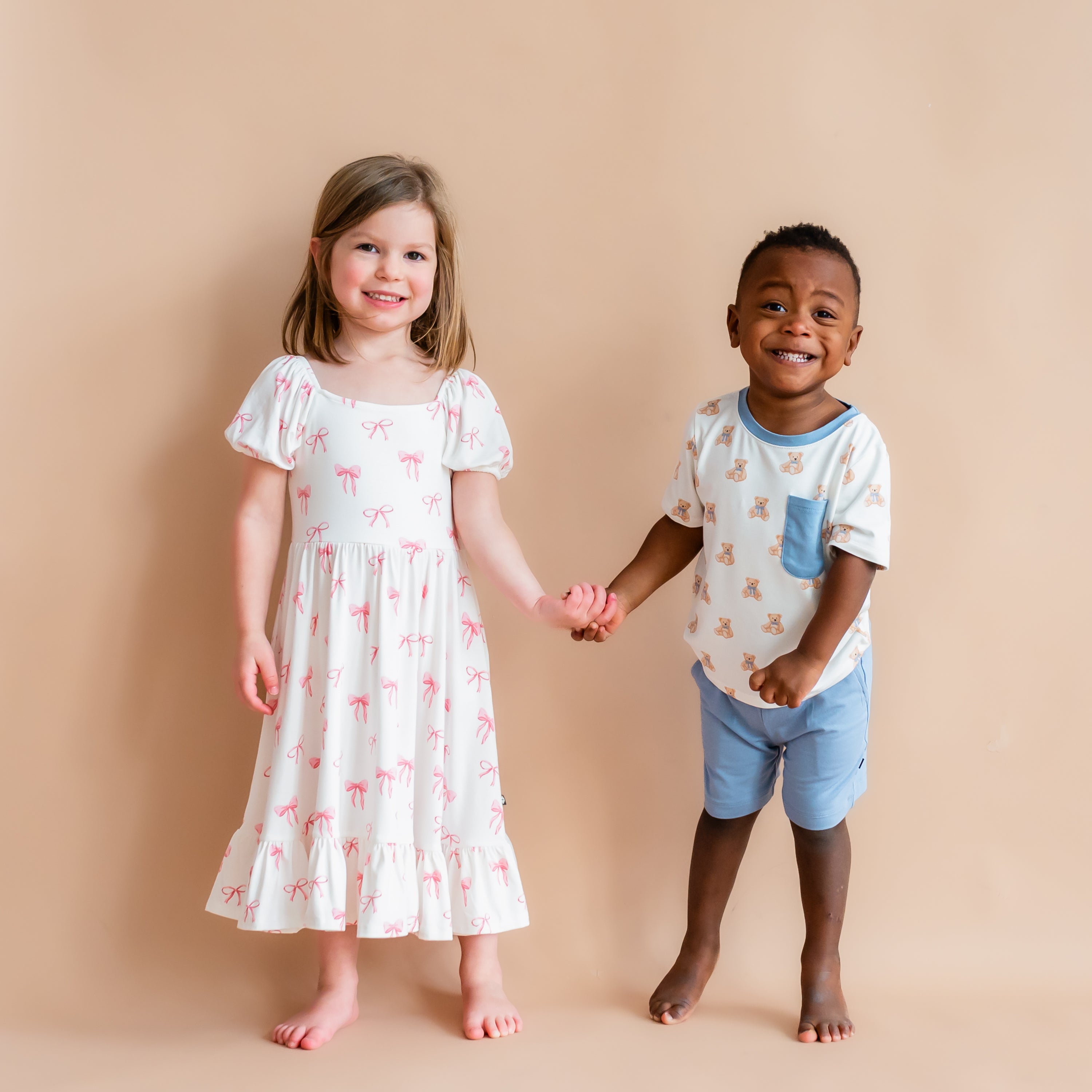 Girl modeling Puff Sleeve Twirl Dress in Bow and boy modeling crew neck tee in Teddy Bear