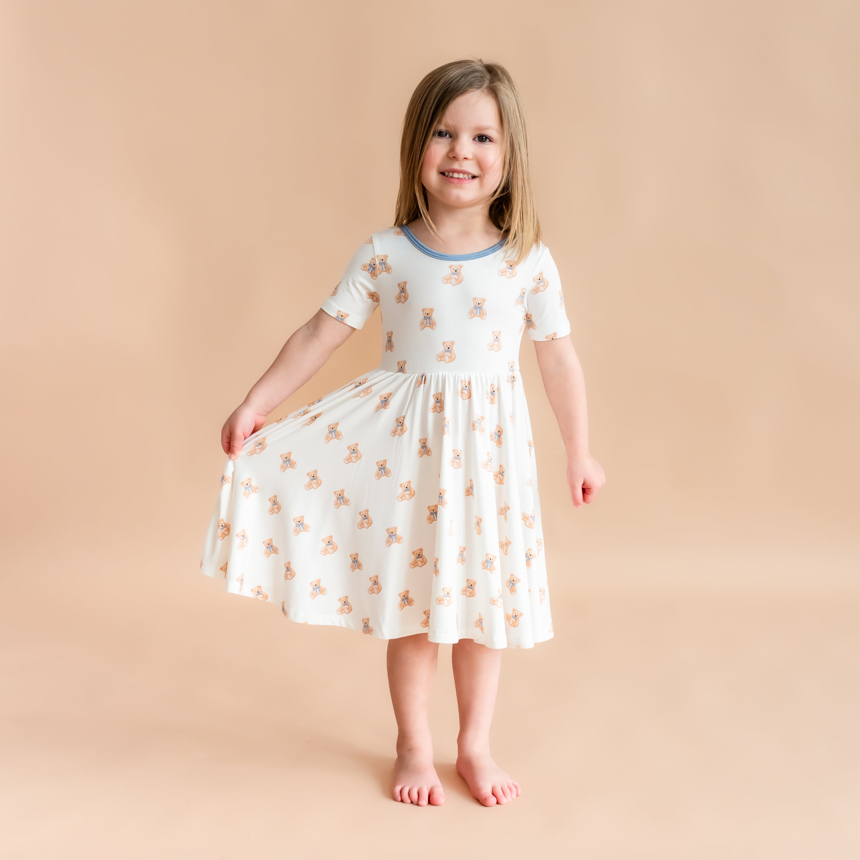 Girl wearing Twirl Dress in Teddy Bear holding out dress