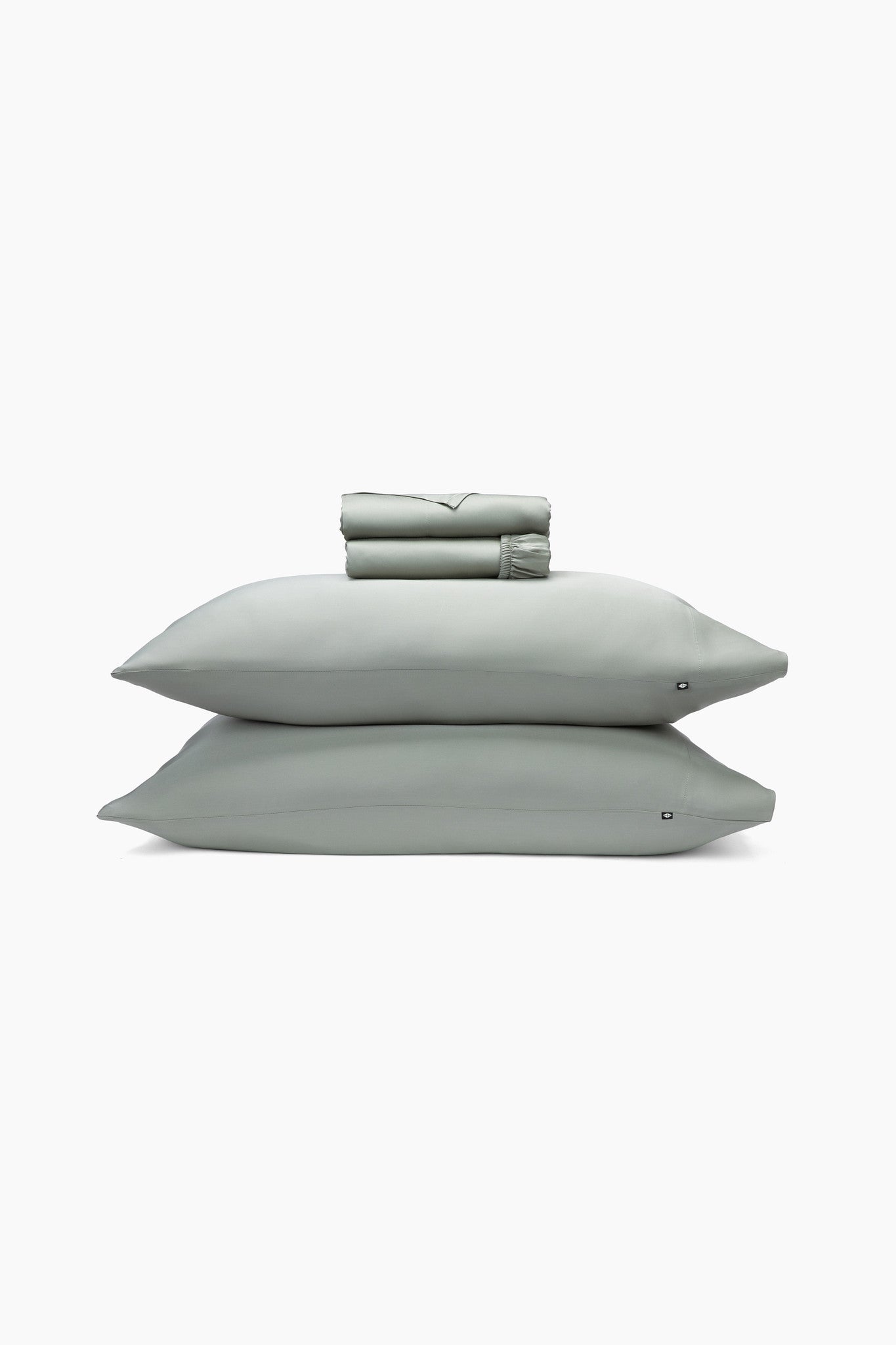 Set of light green bedding including a folded sheet, two pillows, and a sheet on a white background.