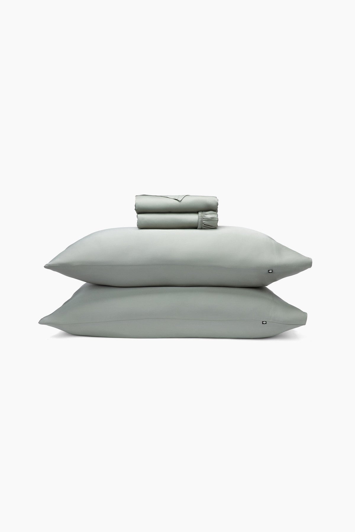 Set of light green bedding including a folded sheet, two pillows, and a sheet on a white background.