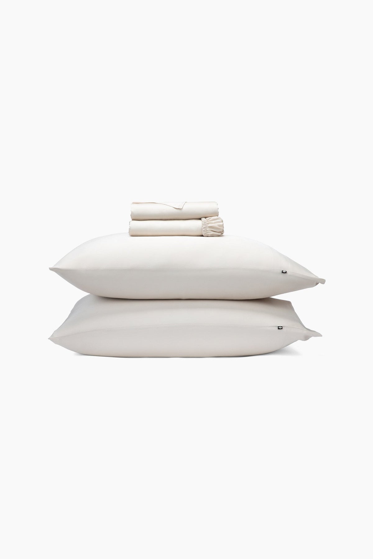 Stack of champagne pillows and folded sheets on a white background