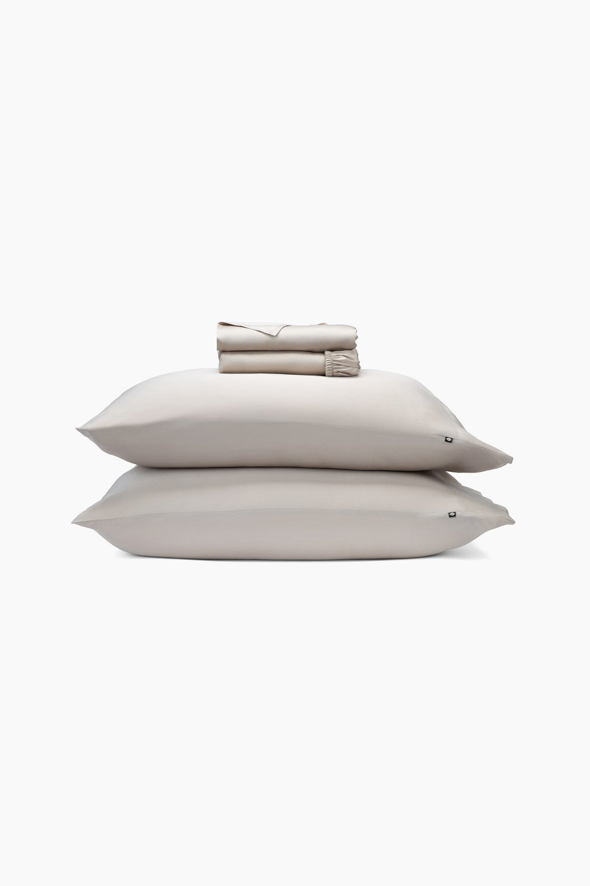 Beige pillows and folded sheets on a white background
