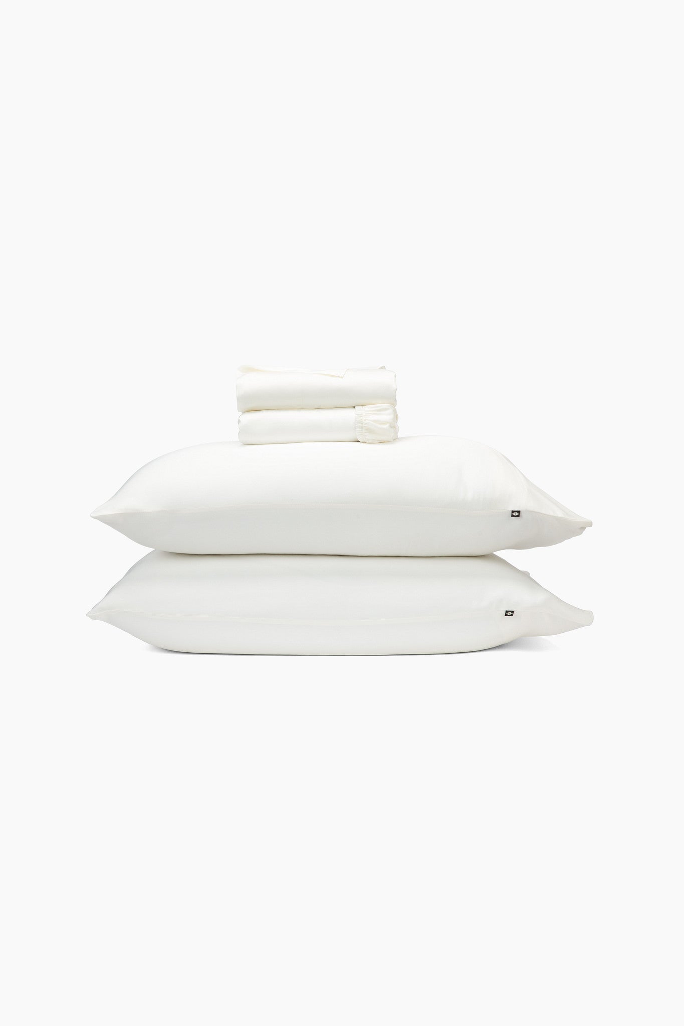 Stack of white pillows and folded sheets on a white background