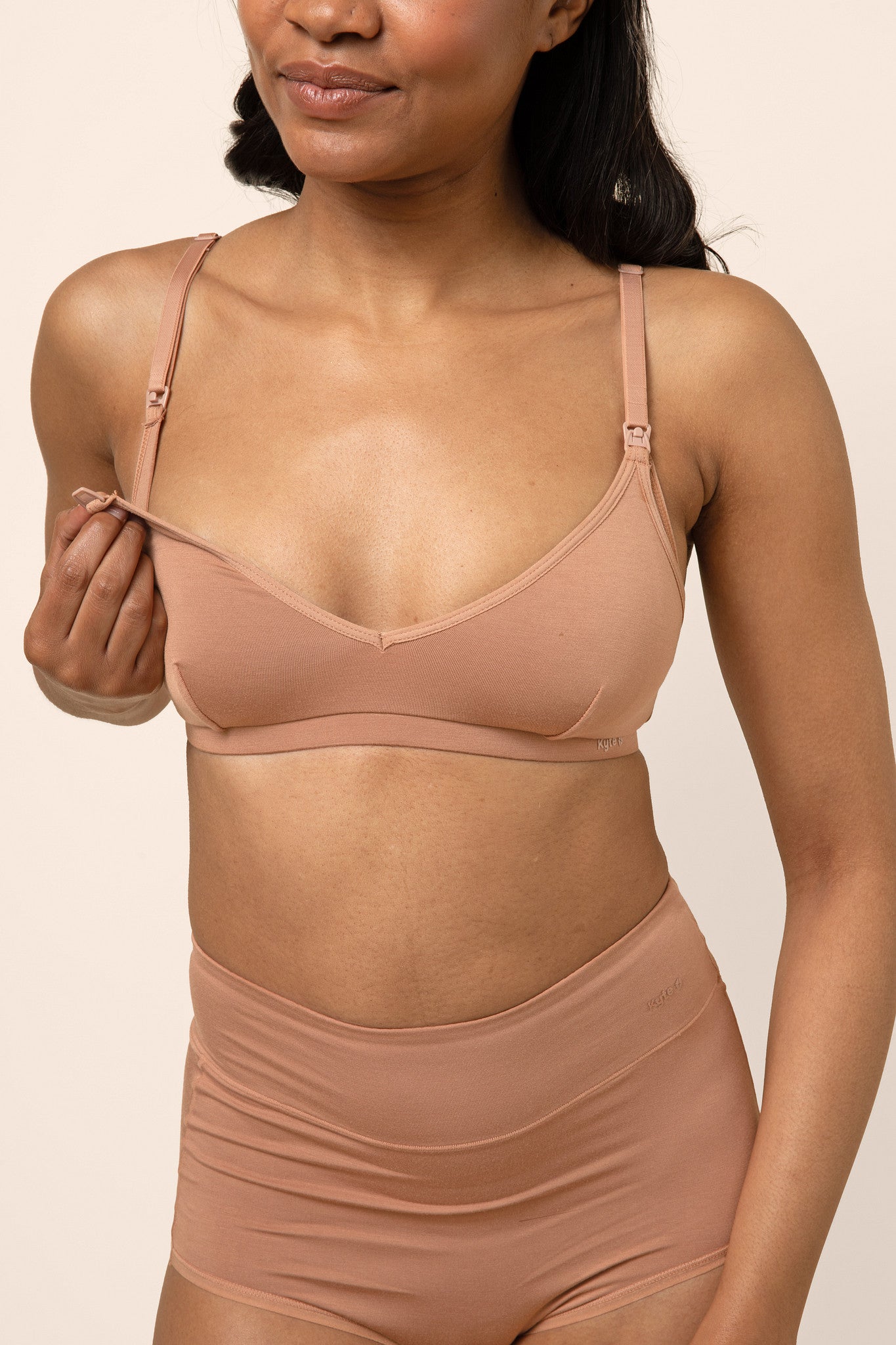 Female modeling the Women's Nursing Bra in Latte unclasping the nursing latch