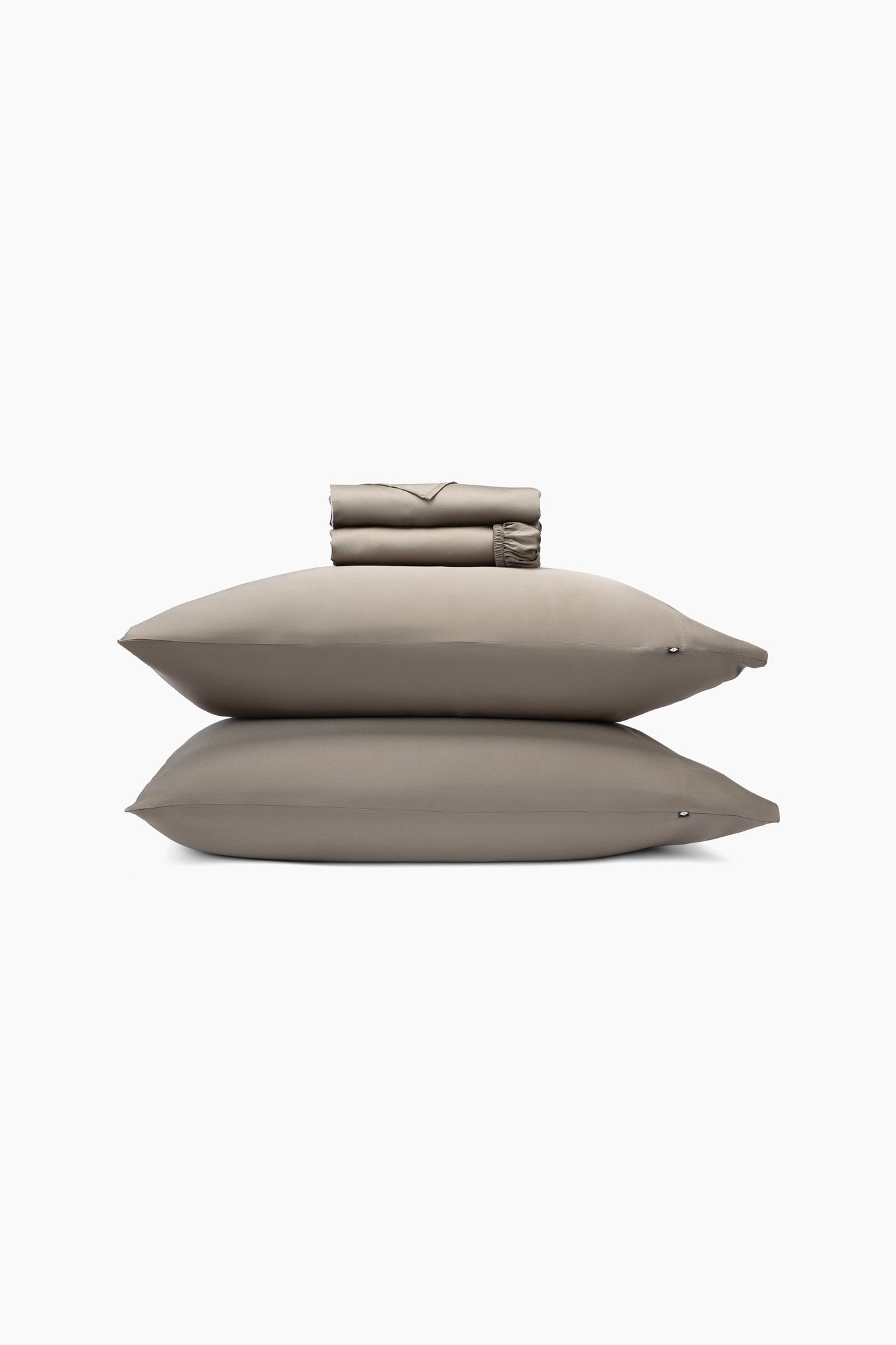 Set of medium brown pillows and a folded sheets on a white background