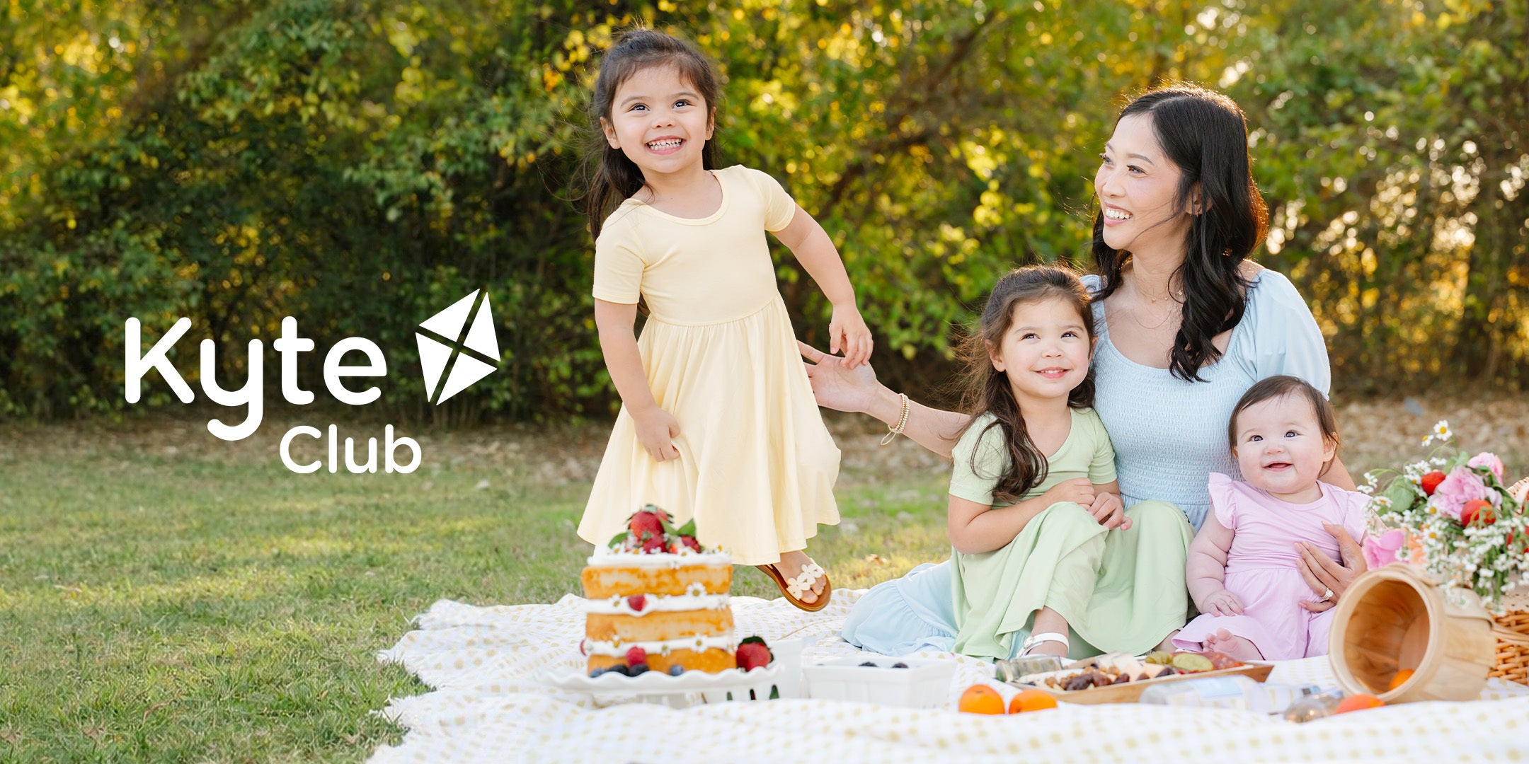 Family of 4 in pastel spring apparel at a picnic with Kyte Club logo