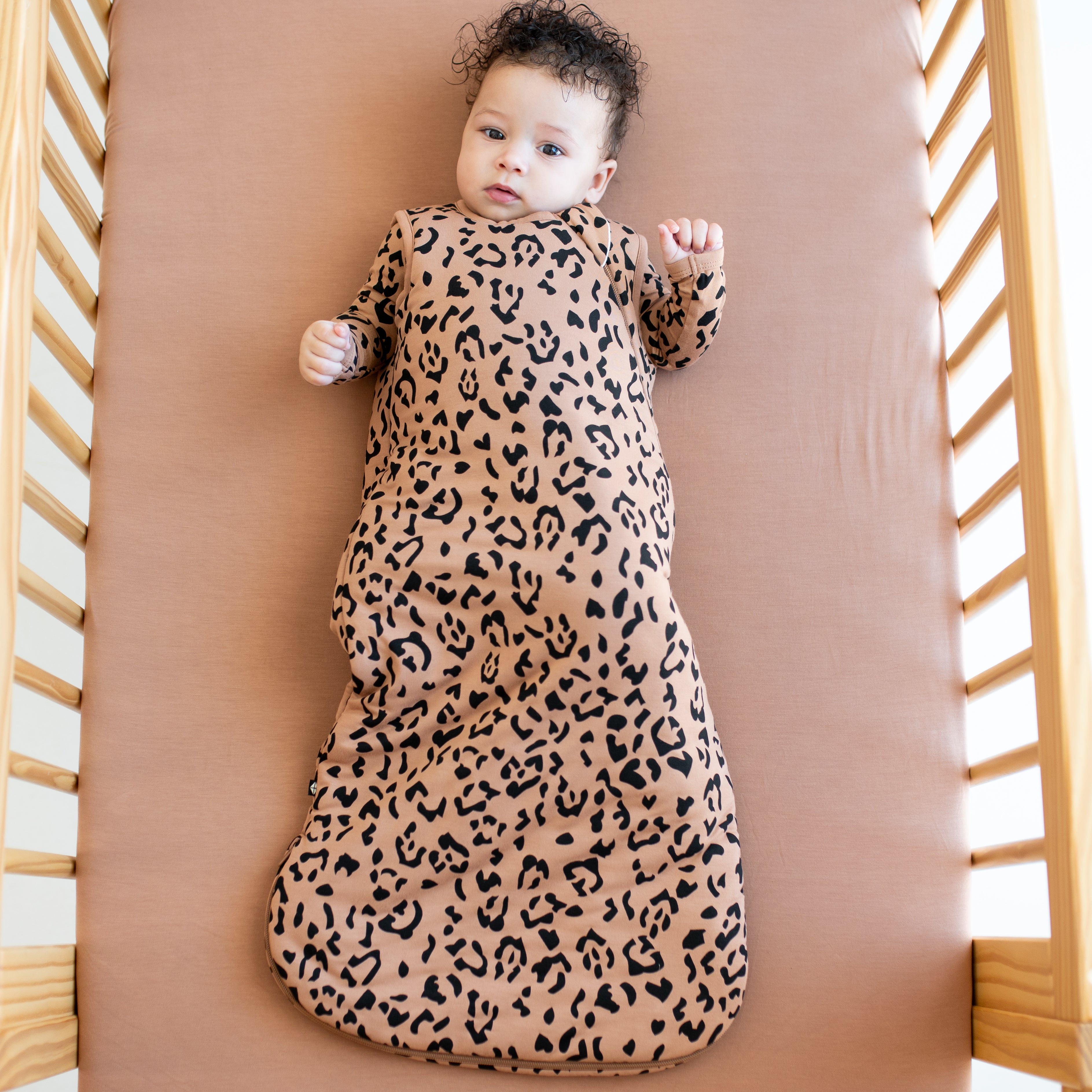 Infant wearing the Sleep Bag in Latte Leopard 2.5 with matching baby pajamas