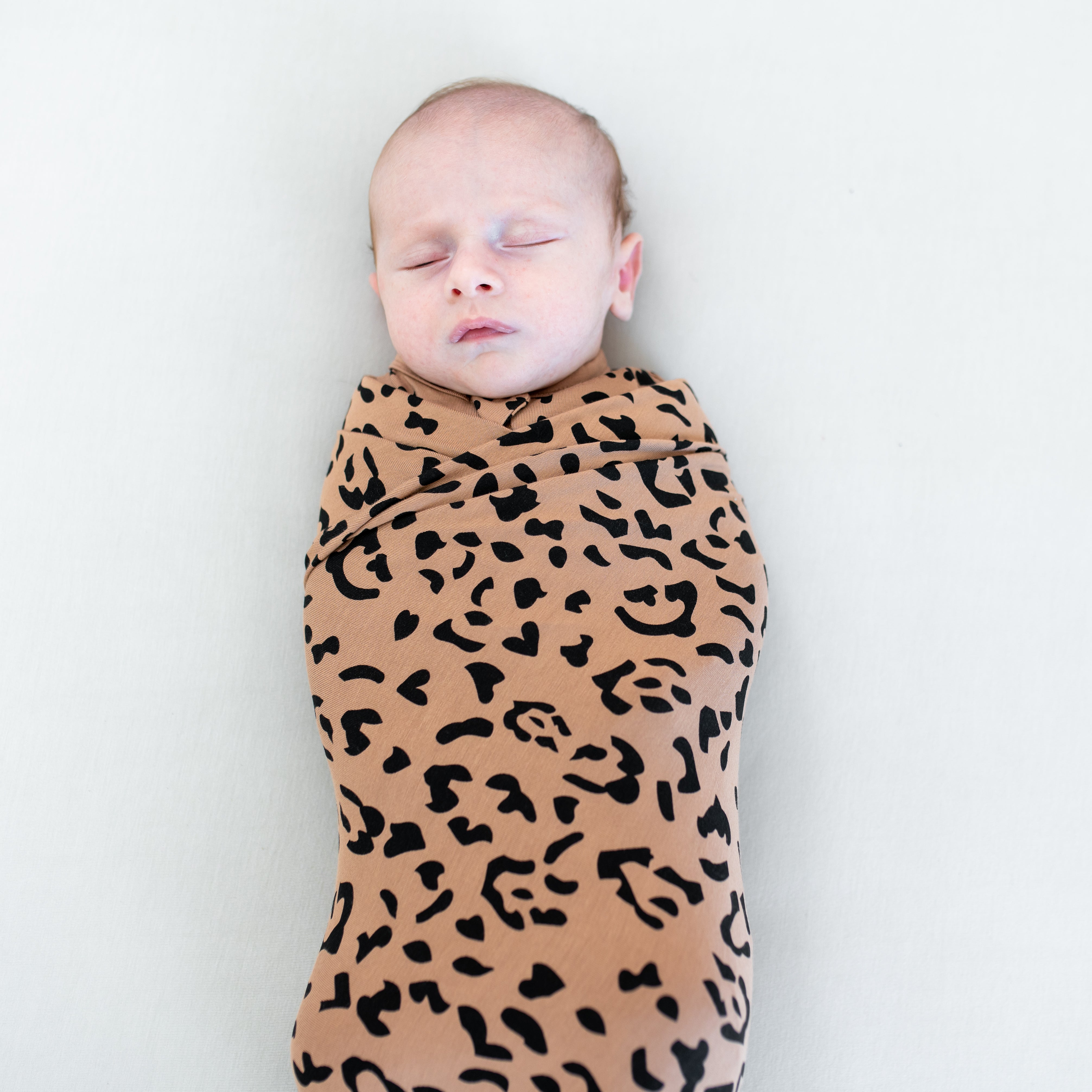 Close up of sleeping baby swaddled in the Swaddle Blanket in Latte Leopard