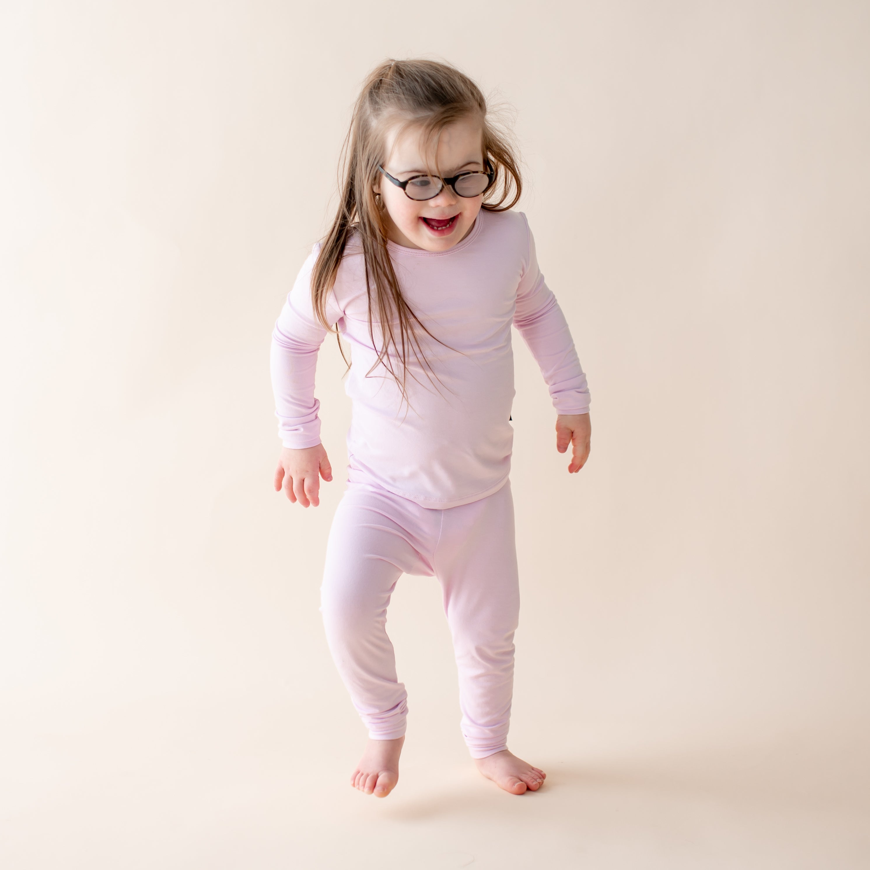 Child wearing light purple pajamas on a plain background