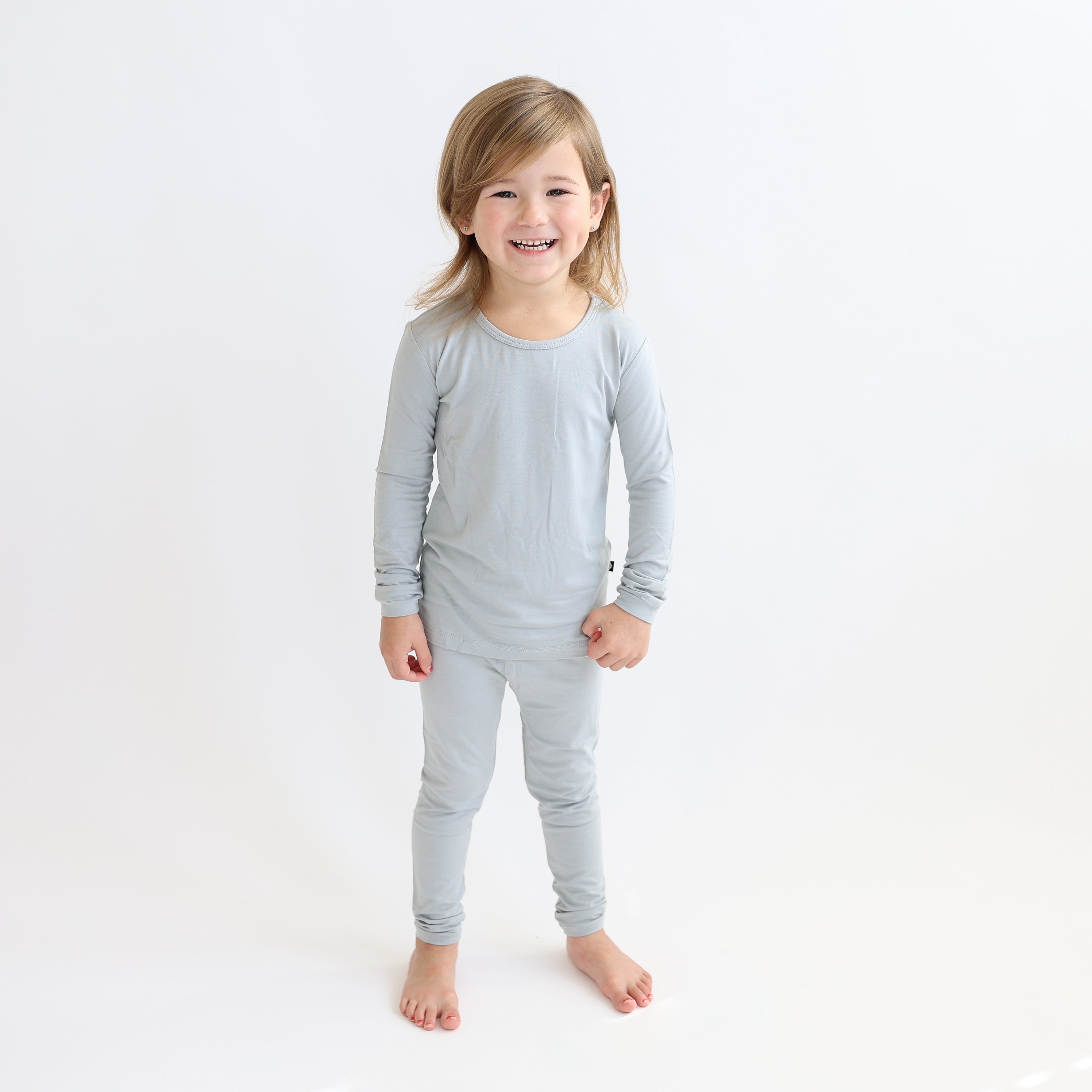 Child wearing a gray long-sleeve shirt and pants pajama set on a white background