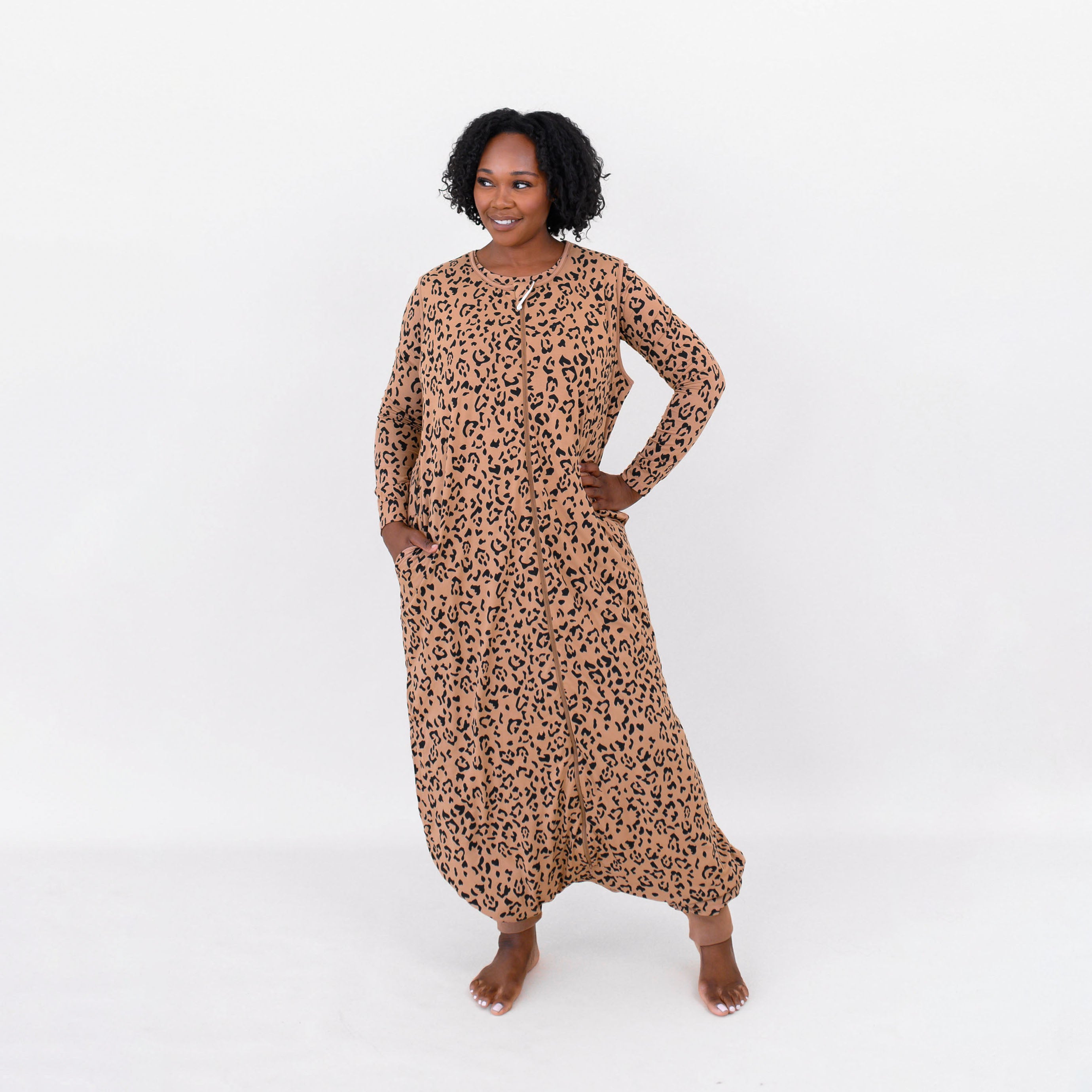 Female standing looking off to the side wearing the Adult Sleep Bag Walker in Latte Leopard and matching women's jogger set