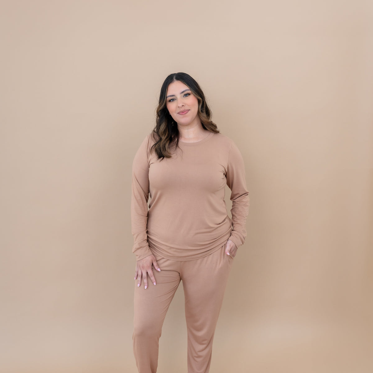 Smiling female model standing with one hand in the pocket of the Women's Jogger Pajama Set in Latte