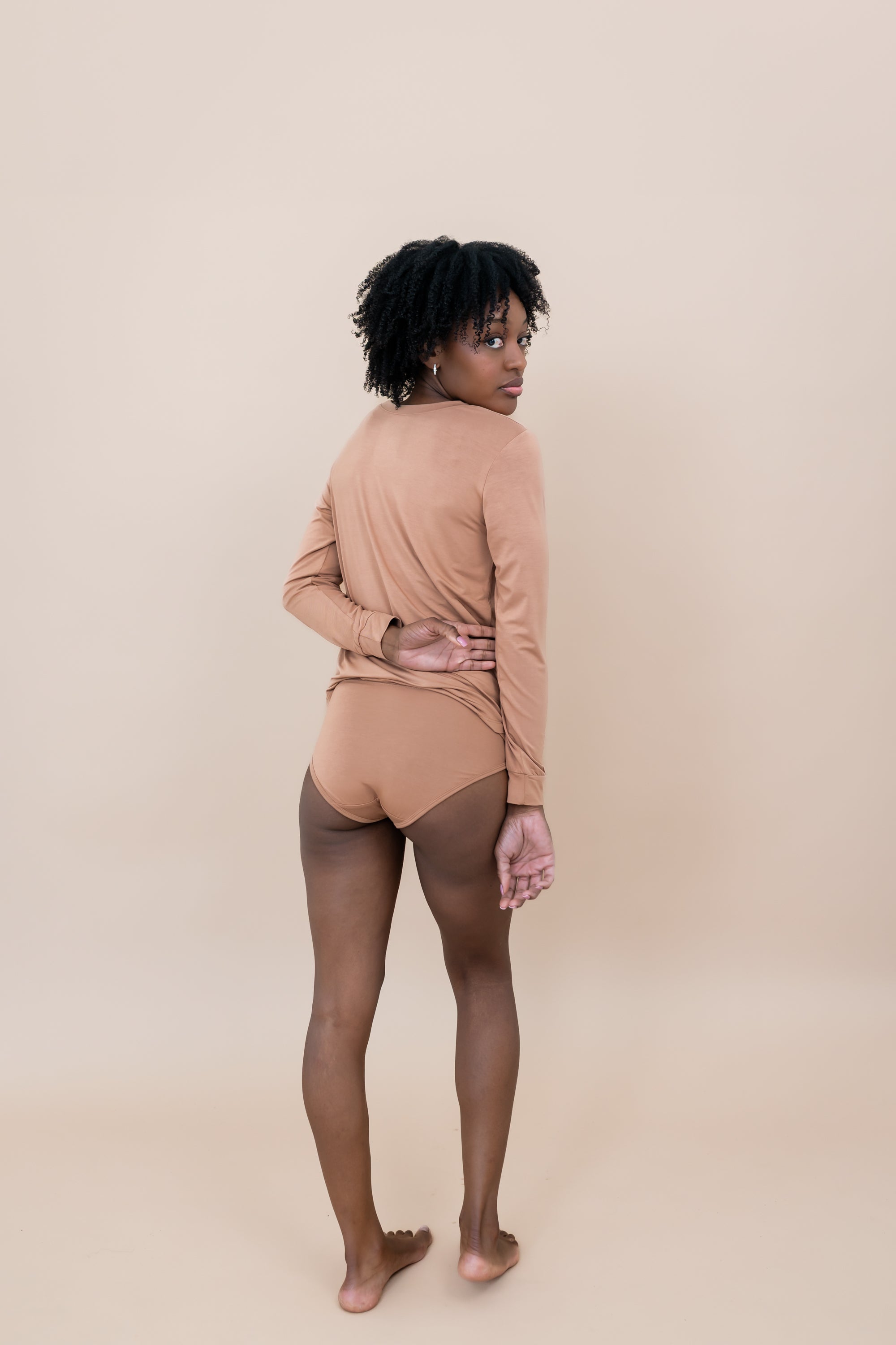 Model standing with her back to the camera showing the back of the Women’s Underwear in Latte paired with a matching top from the women's jogger set