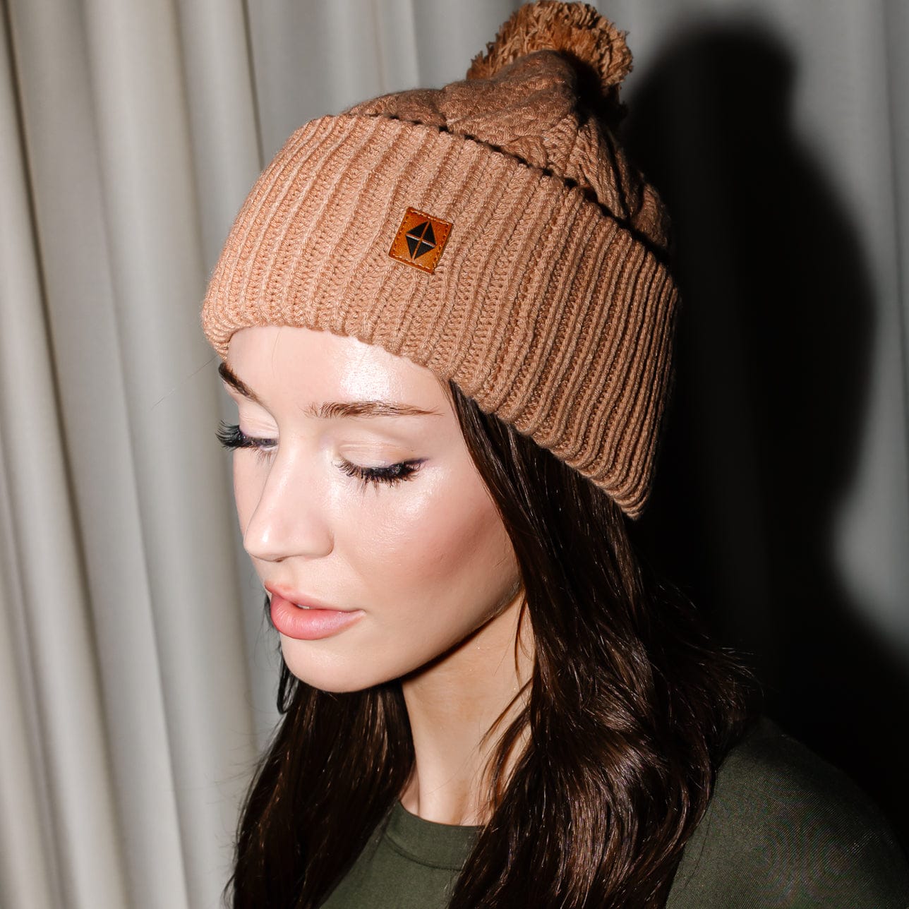 Close up of the Cable Knit Adult Pom Beanie in Latte shown on a female model