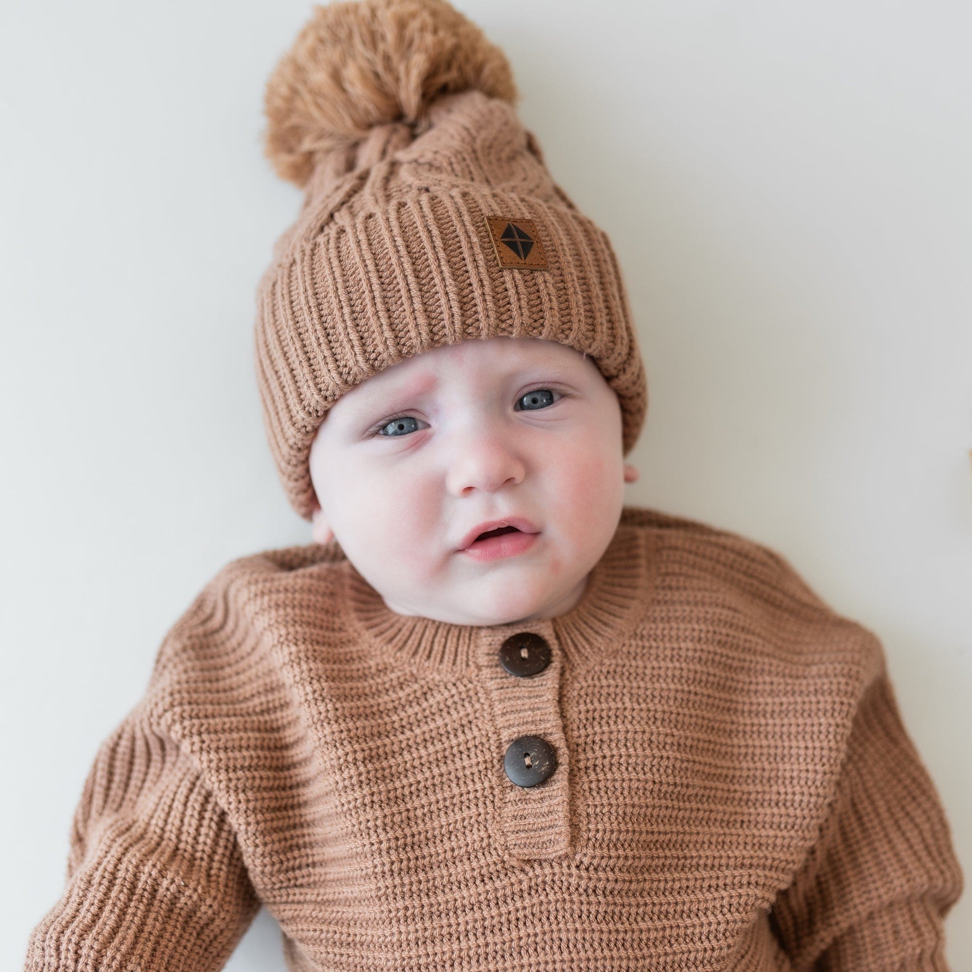 Close up of an infant wearing the Chunky Cable Knit Beanie in Latte