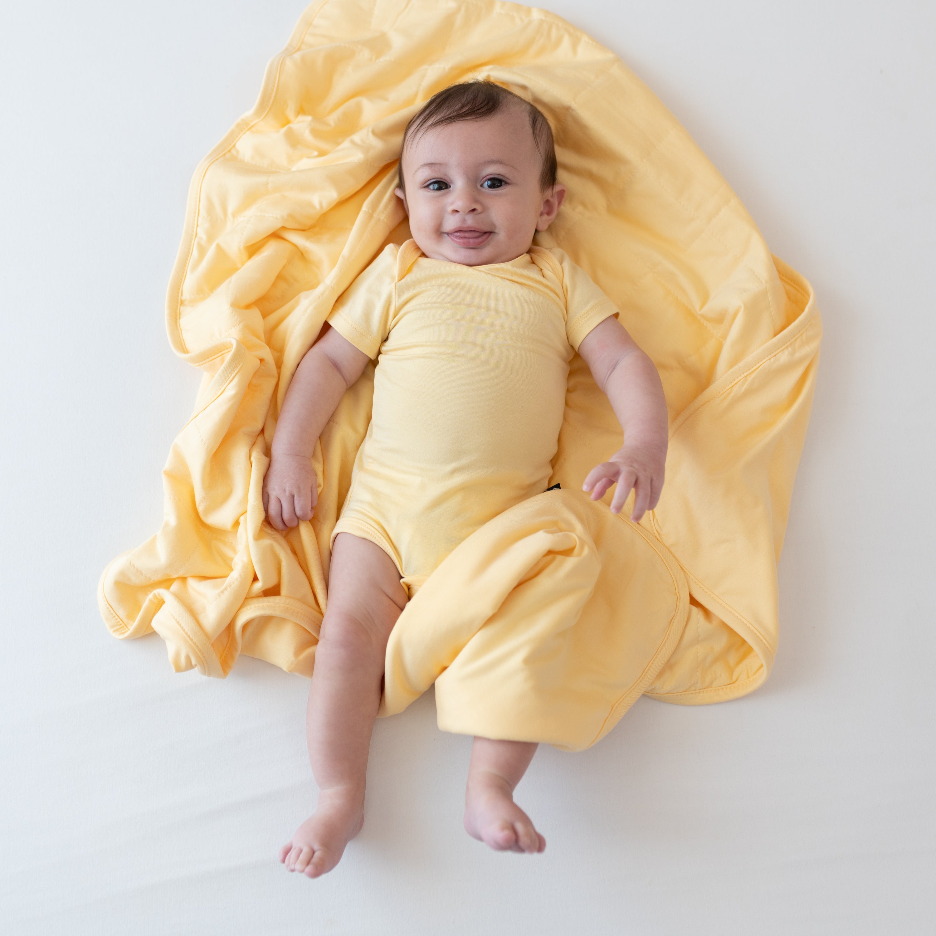 Baby wearing Bodysuit laying on matching yellow Baby Blanket in Lilikoi TOG 1.0