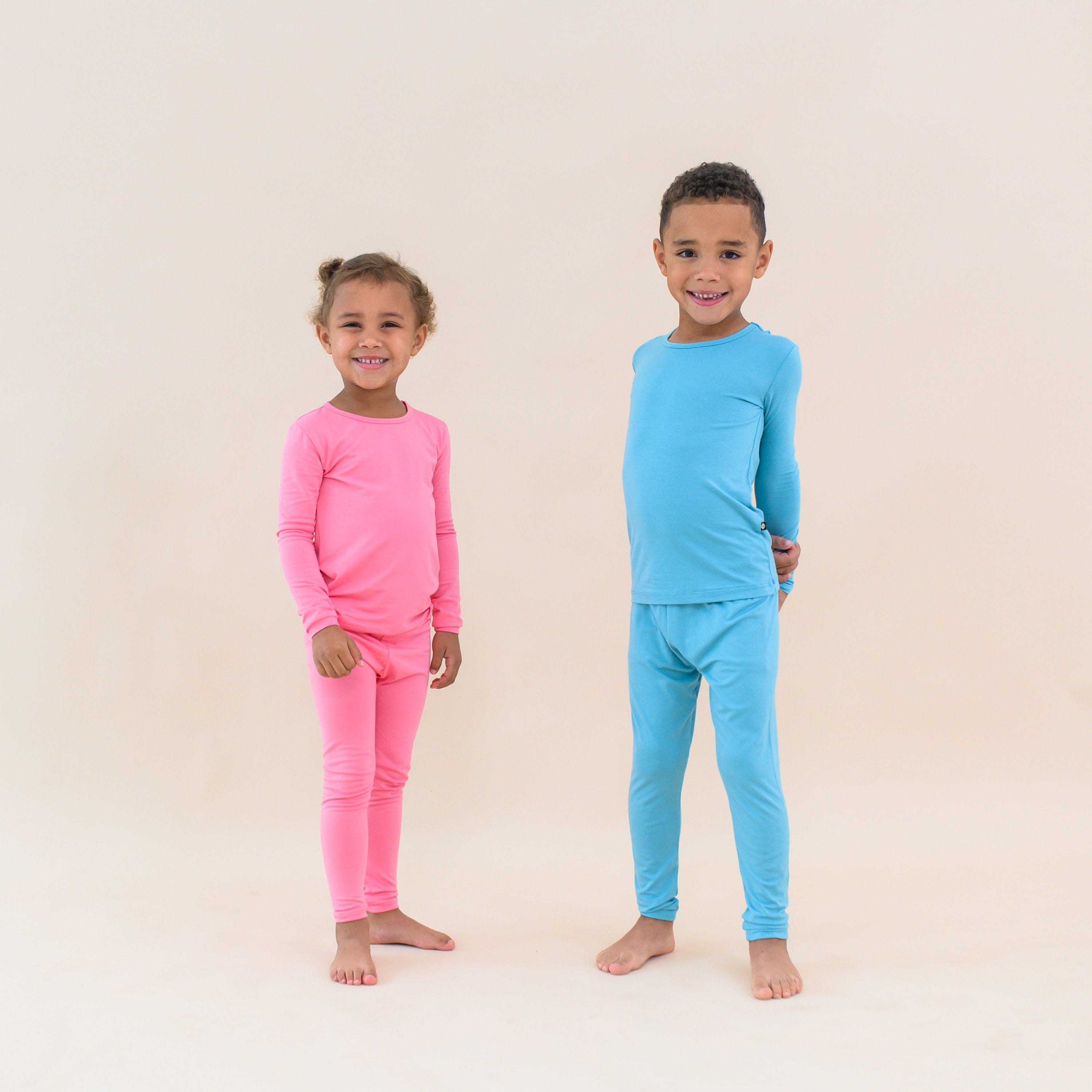 Toddlers modeling long sleeve pajamas in guava and makai