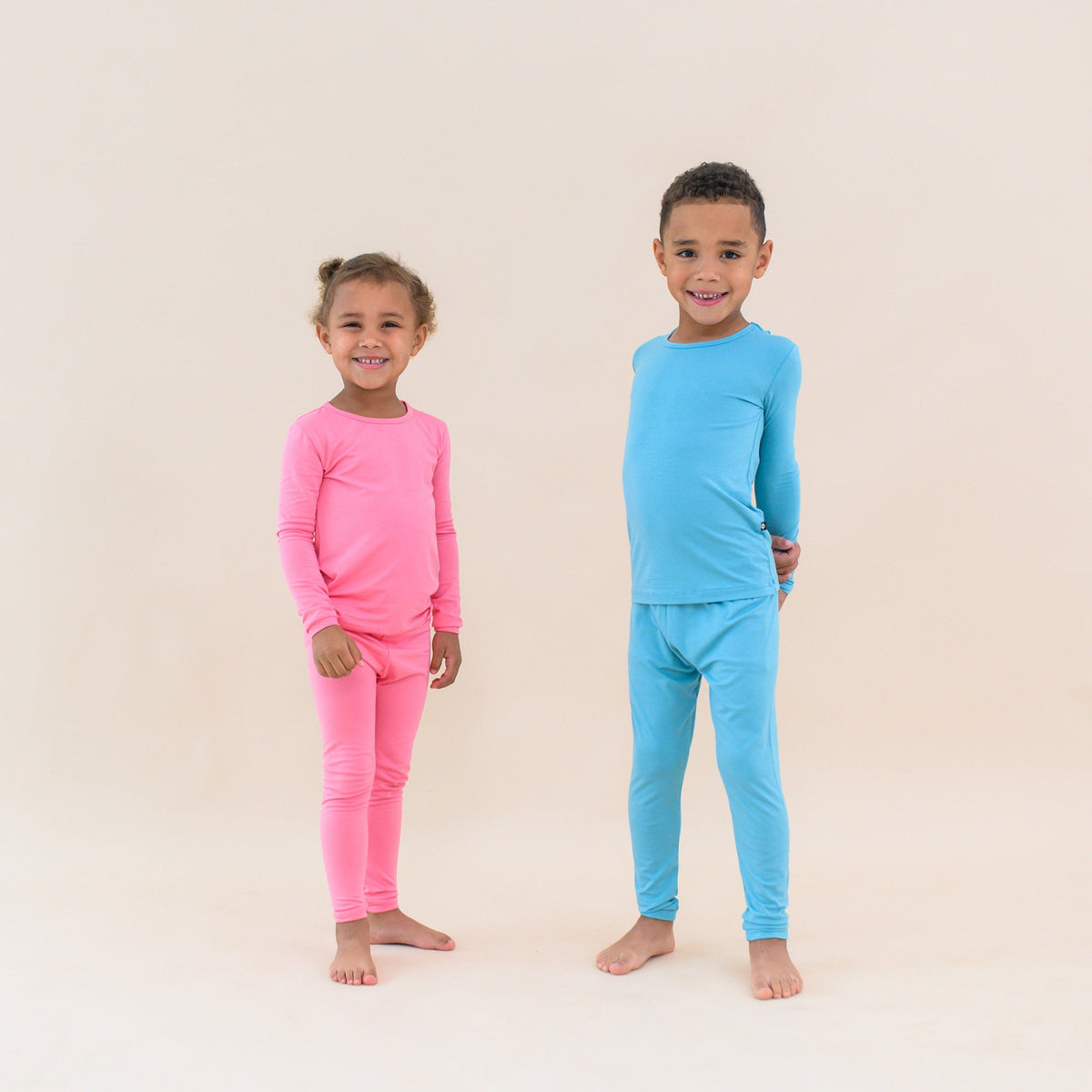 Toddlers modeling long sleeve pajamas in guava and makai