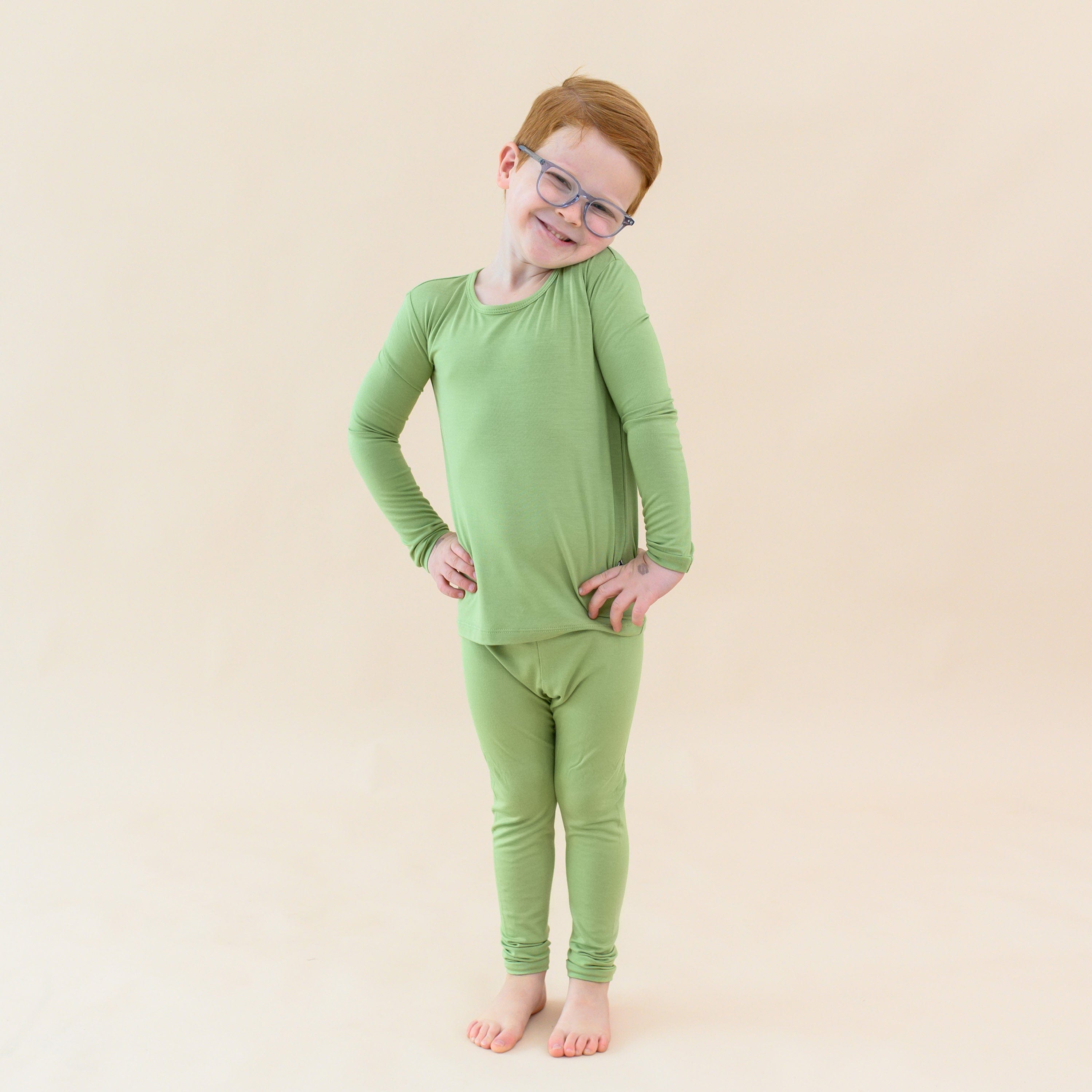 Toddler modeling long sleeve pajamas in honu green