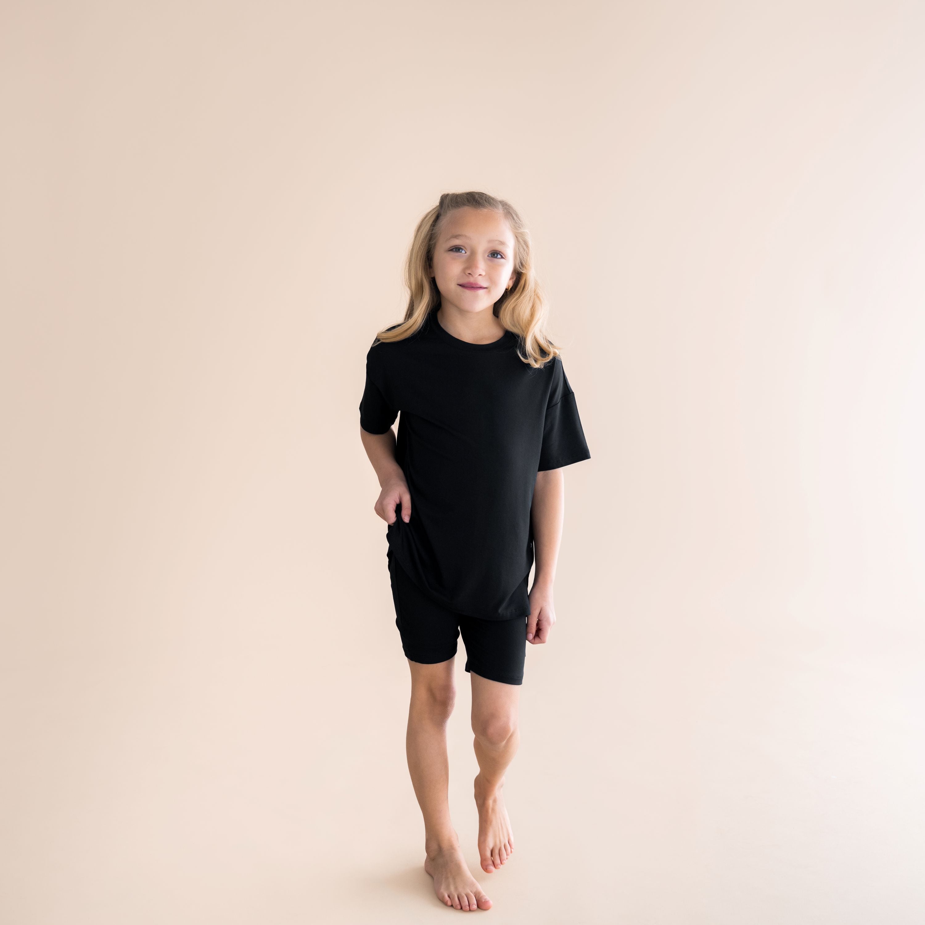 Young girl walking forward wearing the Toddler Biker Short Set in Midnight