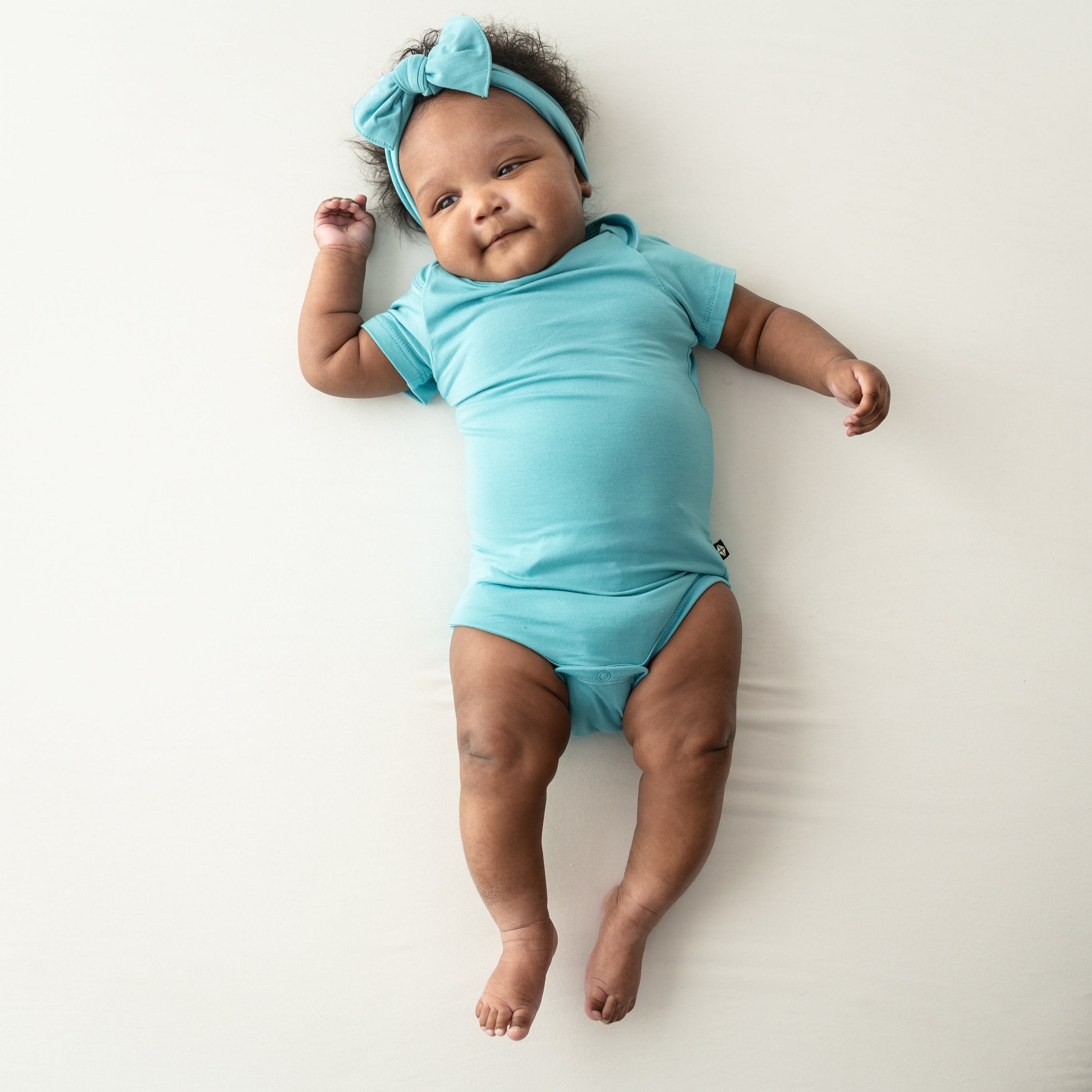 baby wearing short sleeve bodysuit and bow in makai