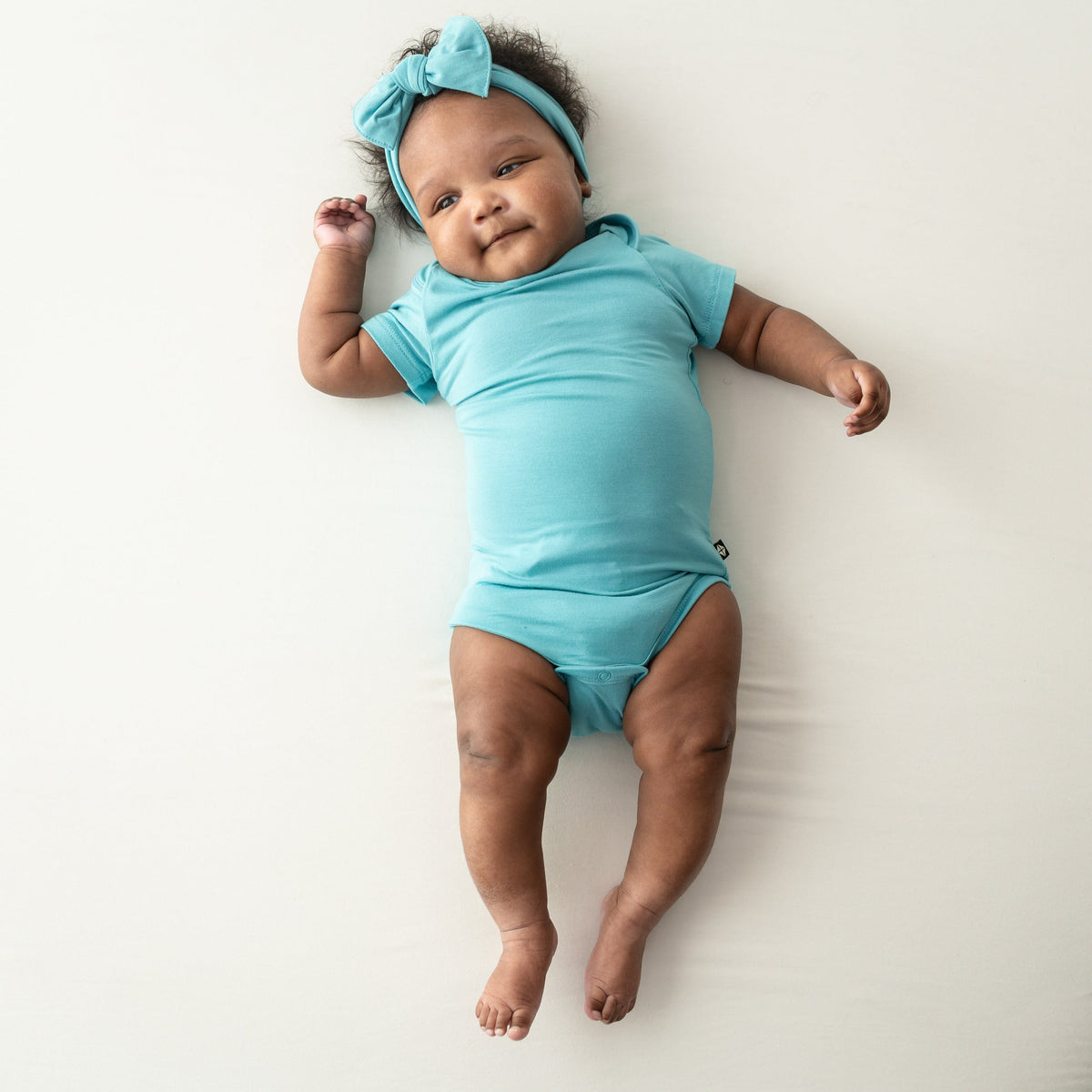 baby wearing short sleeve bodysuit and bow in makai